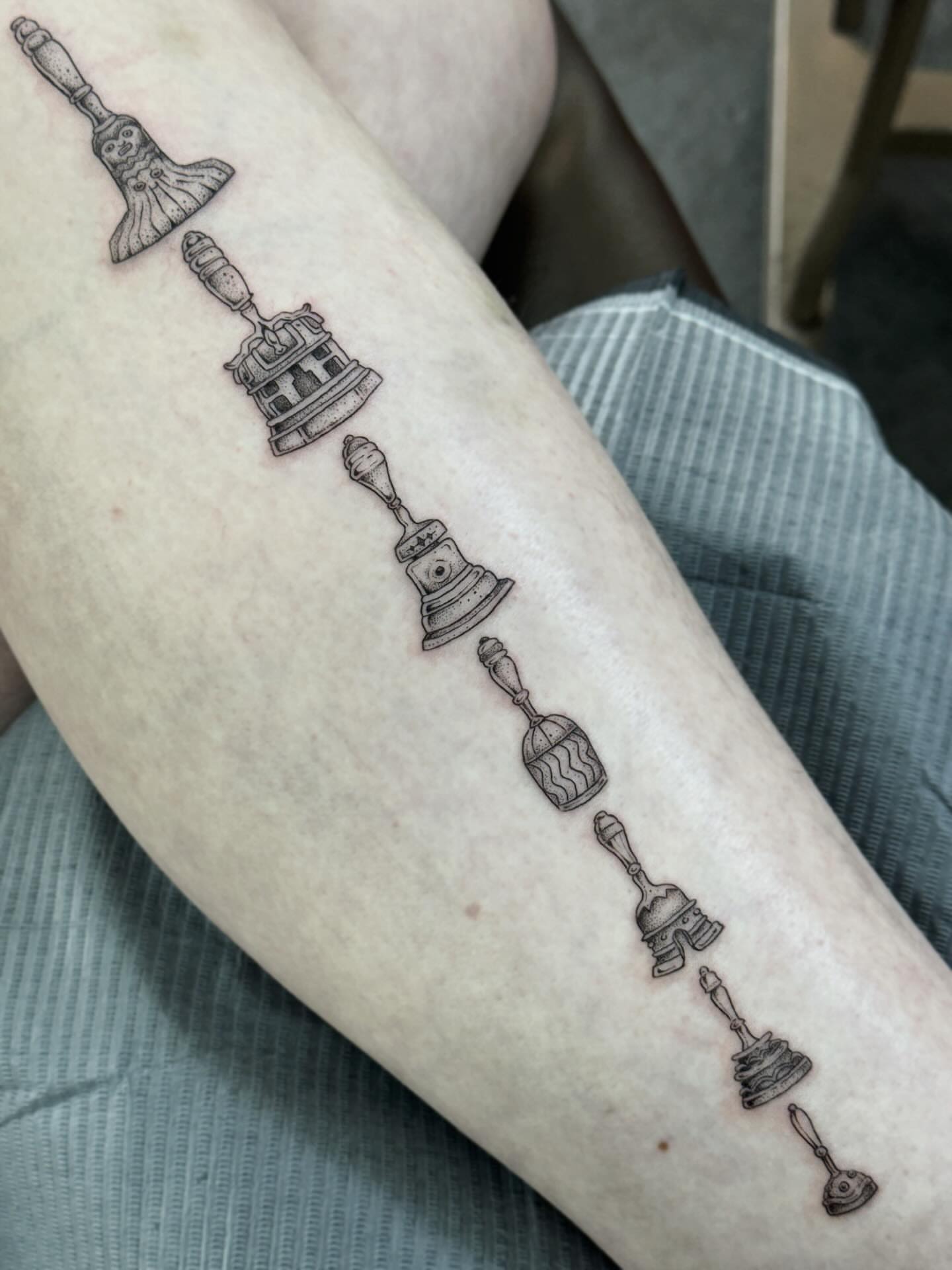 Bell black and grey tattoo on the forearm by Writhe Grey