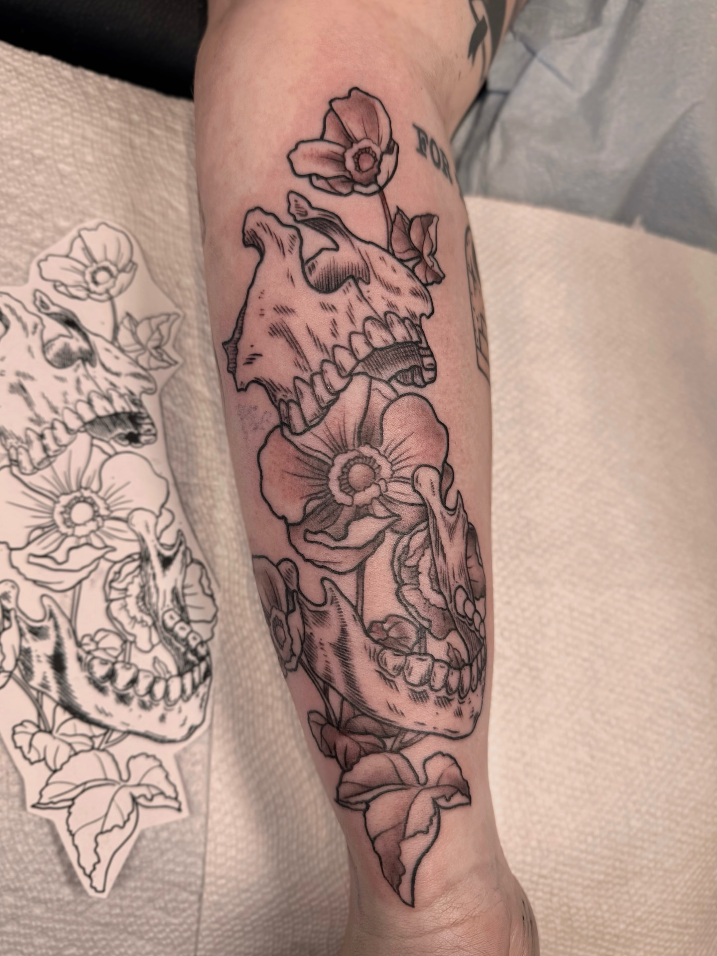 Skull and flowers realism tattoo on the forearm by Suda
