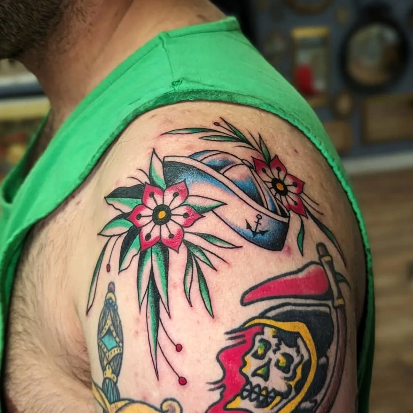 Skull and flowers American traditional tattoo on the shoulder by joseph palladino