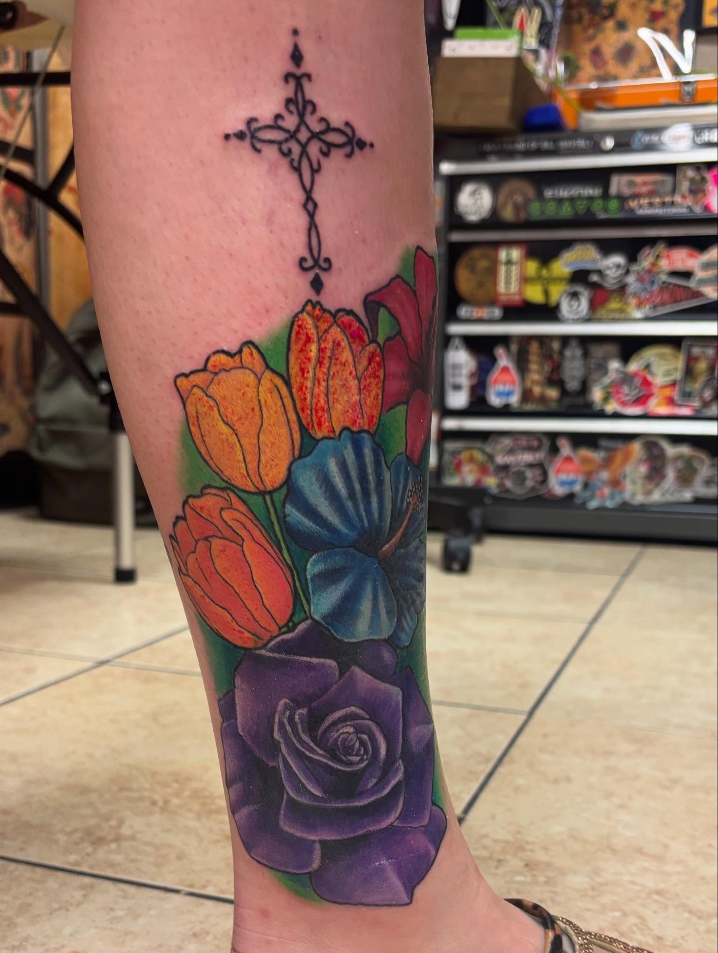 Flowers and cross American traditional tattoo on the forearm by Oscar Cuéllar (Kue-Yar)