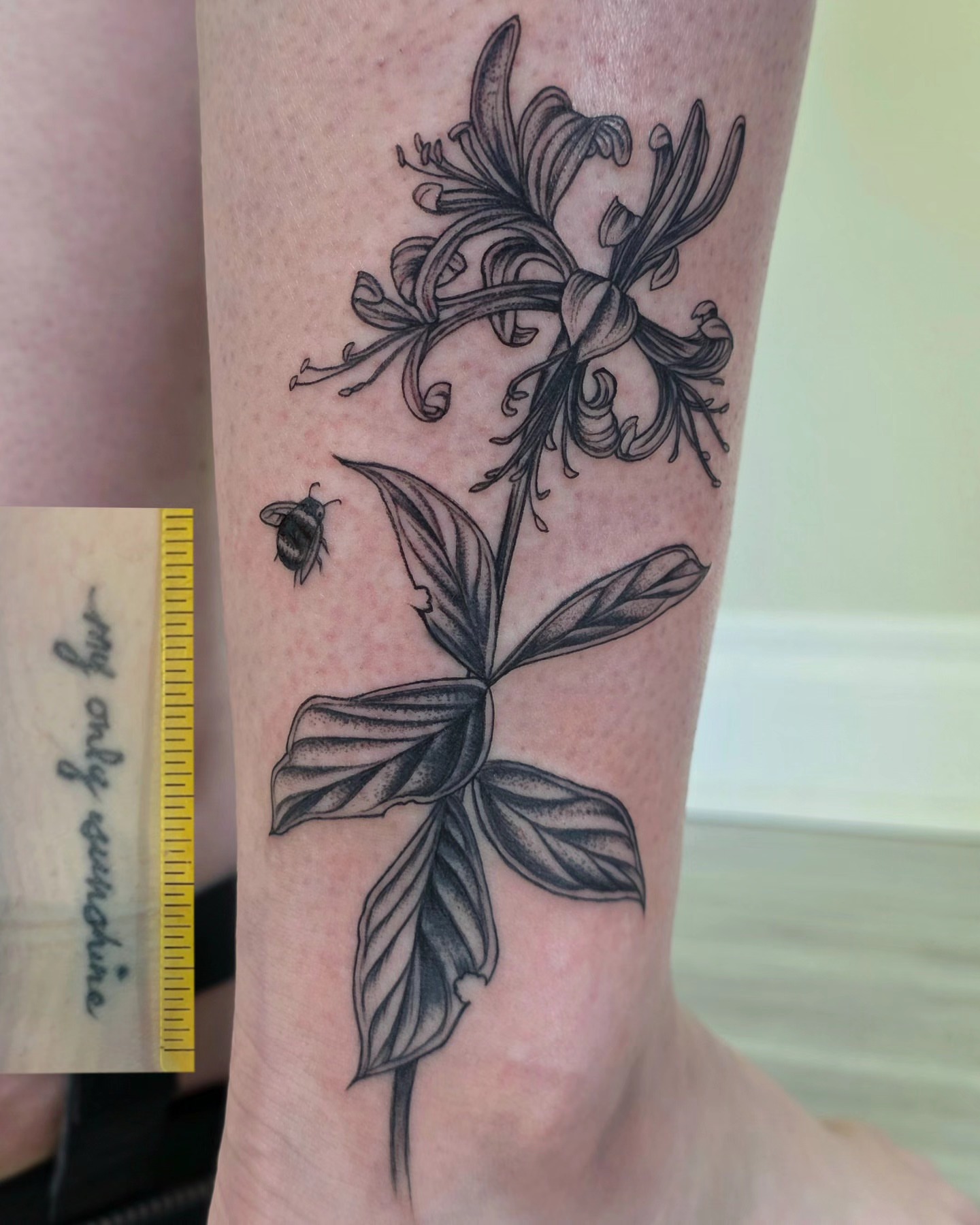 Honeysuckle and bee black and grey tattoo on the forearm by Sierra (cc) Klein