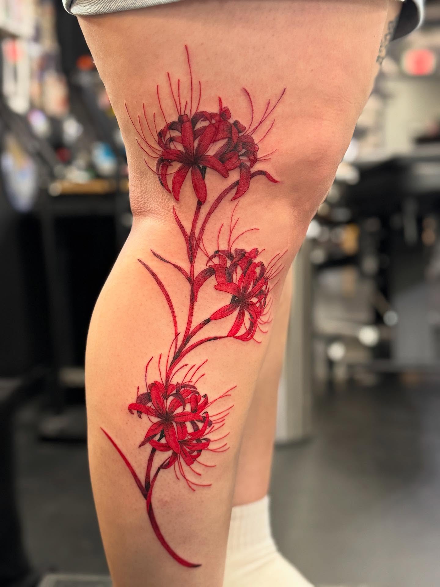 Red spider lilies realism tattoo on the thigh by Marissa Losier
