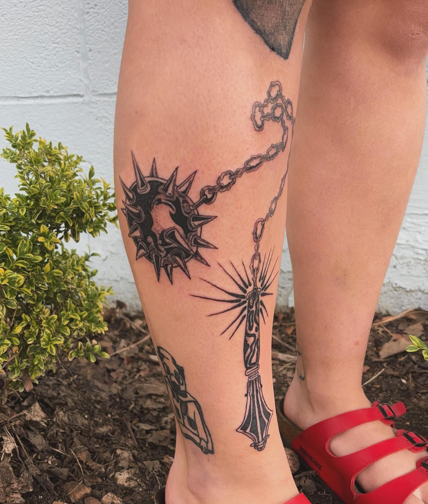 Spiked collar and sword black and grey tattoo on the calf by Ashley Ellerman