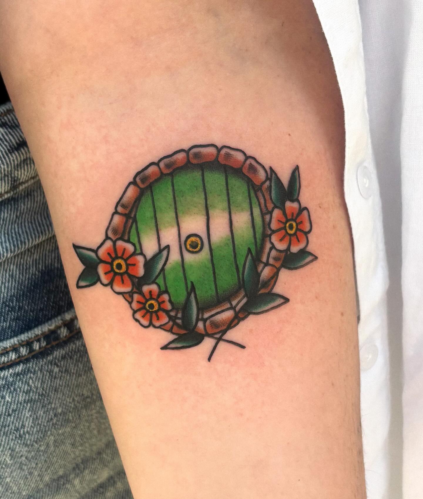 Green hobbit door American traditional tattoo on the forearm by Katelyn Spence