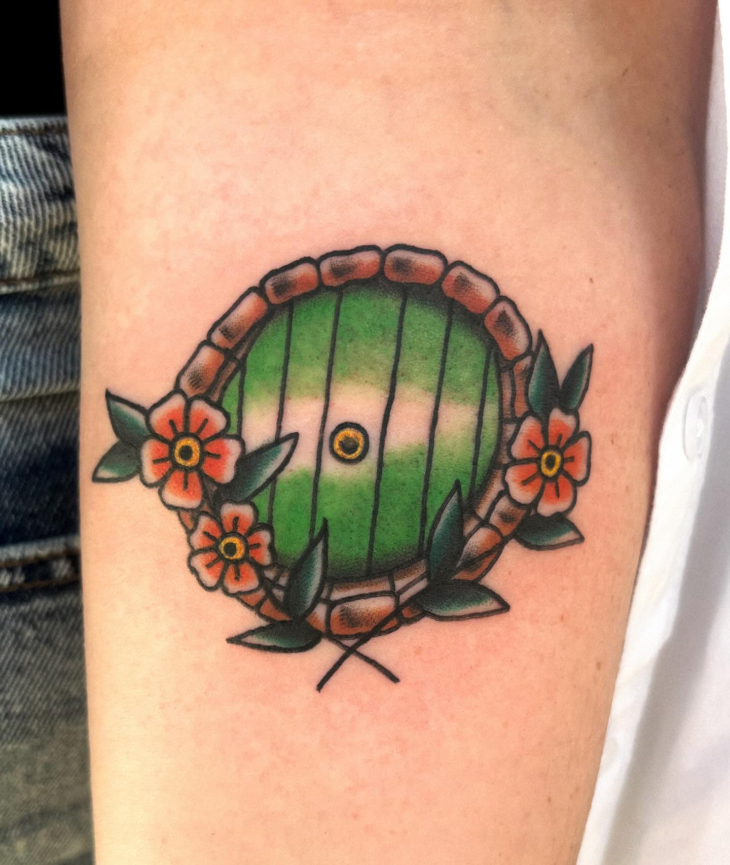 Green hobbit door American traditional tattoo on the forearm by Katelyn Spence