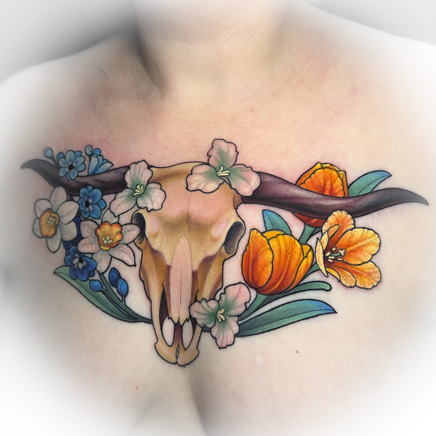 Cow skull with flowers new school tattoo on the chest by Hannah Steele