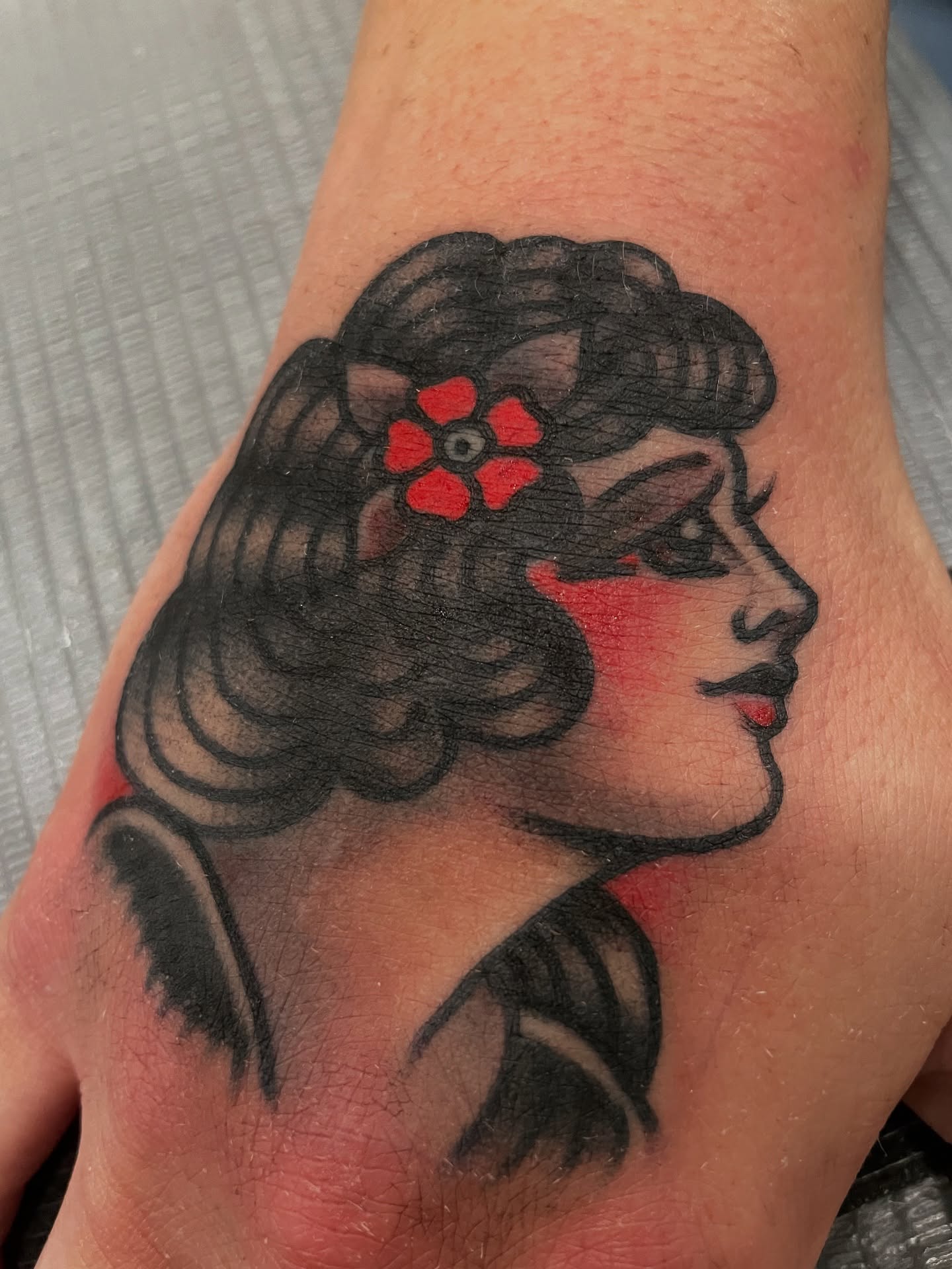 Woman with flower American traditional tattoo on the hand by matt nelson