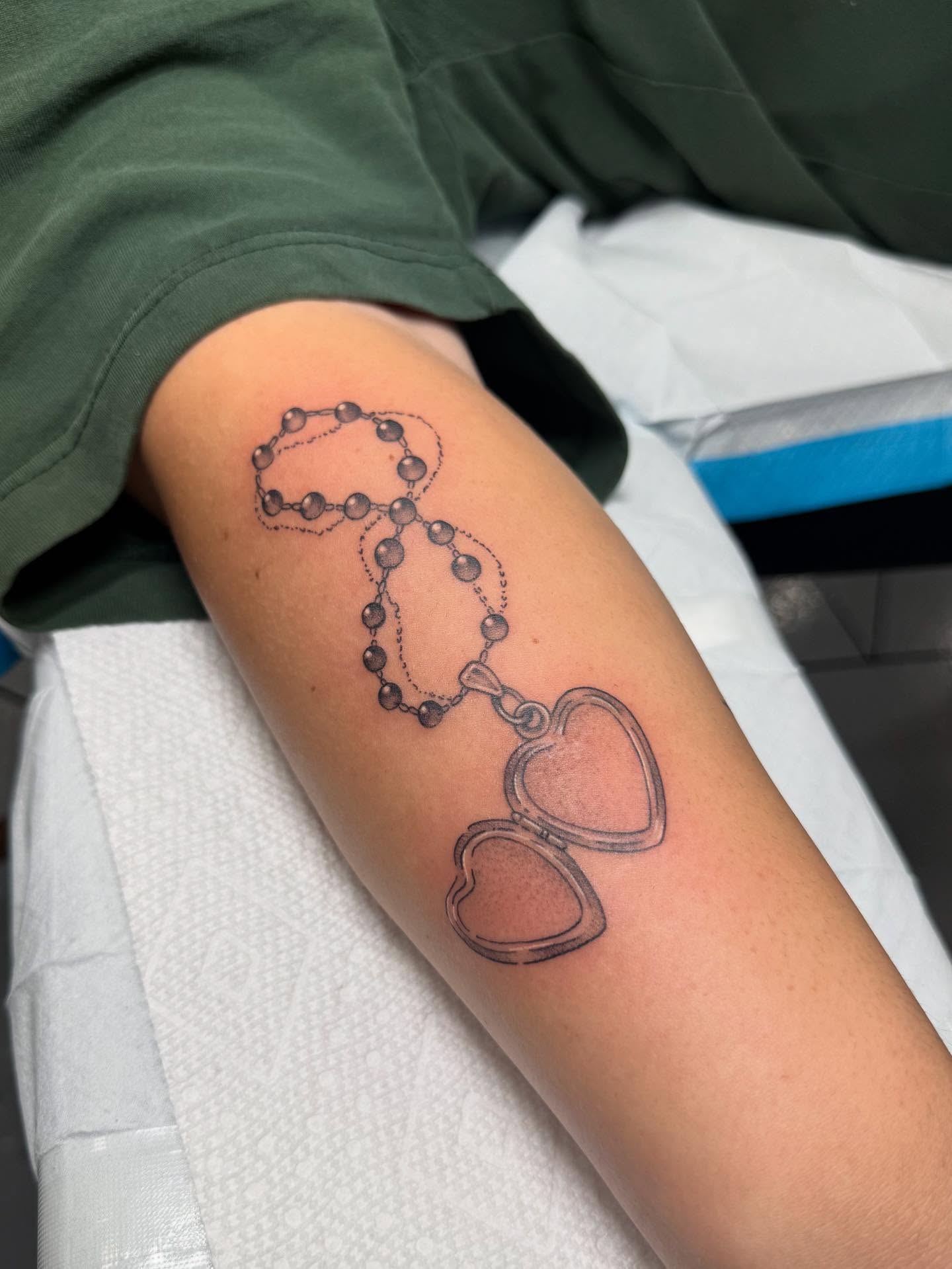 Rosary and heart black and grey tattoo on the forearm by Maddie Jo DeYoung