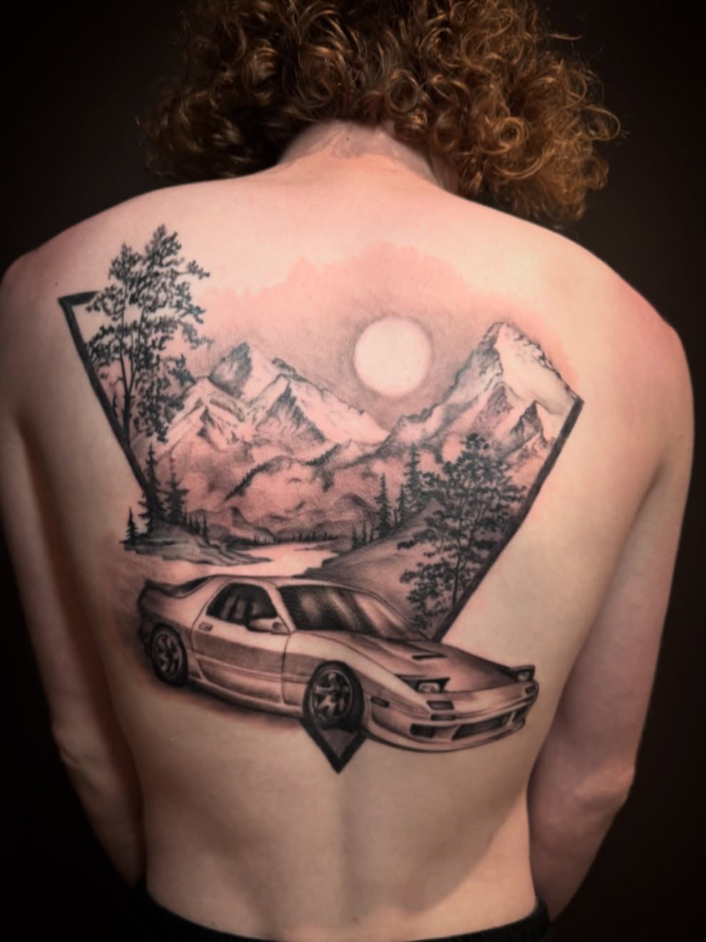 Car and mountain landscape realism tattoo on the back by Brennan Walker, Orem, Utah