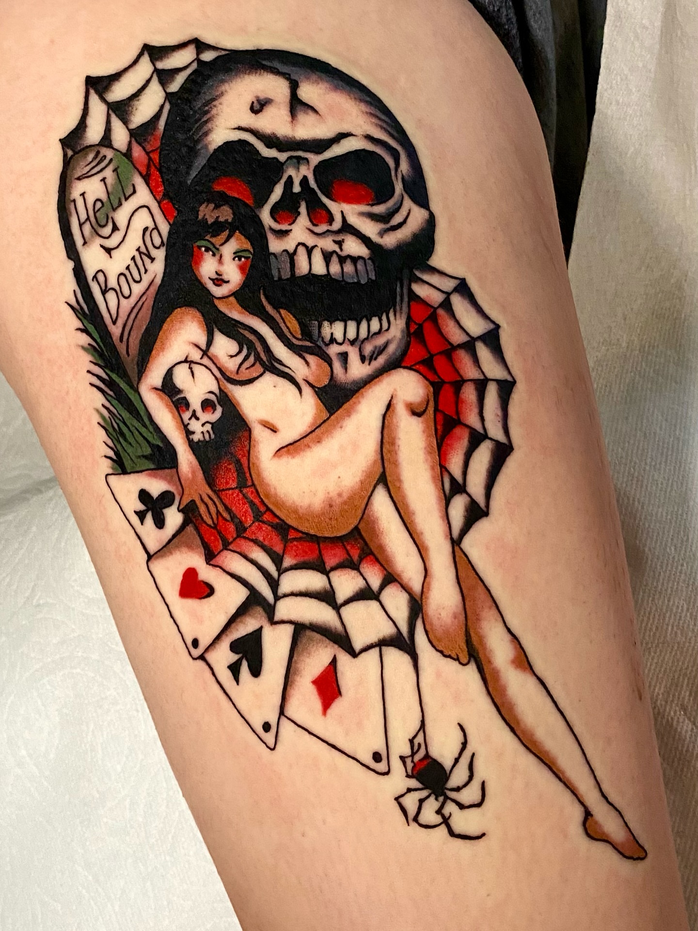 Naked woman with skull American traditional tattoo on the thigh by Haley Tucker, Sebastopol, California