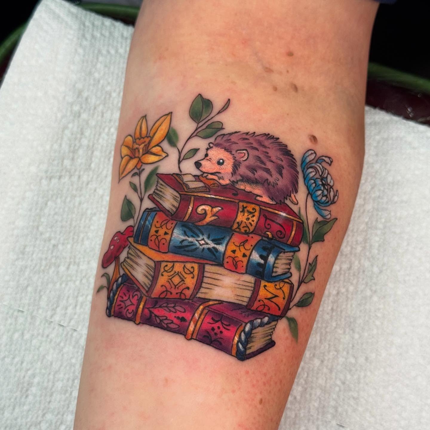Hedgehog with books American traditional tattoo on the forearm by Anna Saveria