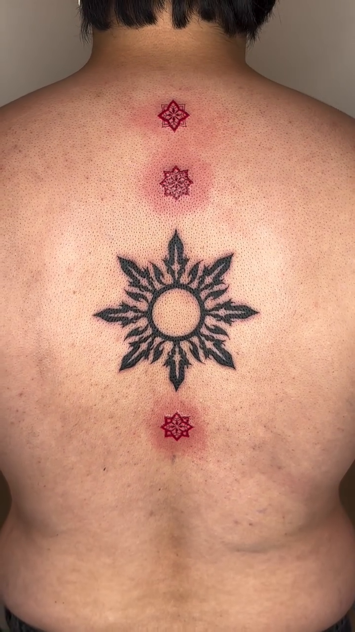 Sun symbol with red accents geometric tattoo on the back by A. Eye Tat