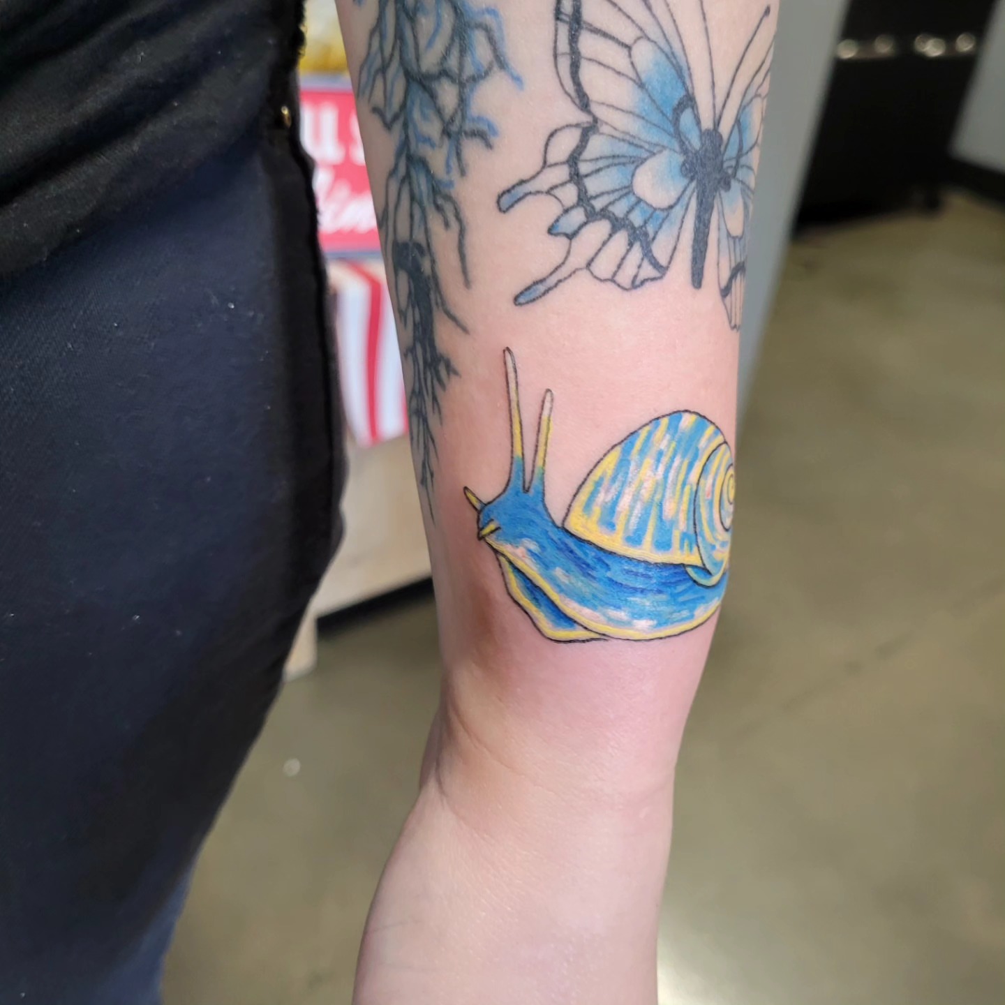 Snail watercolor tattoo on the forearm by Aspen C