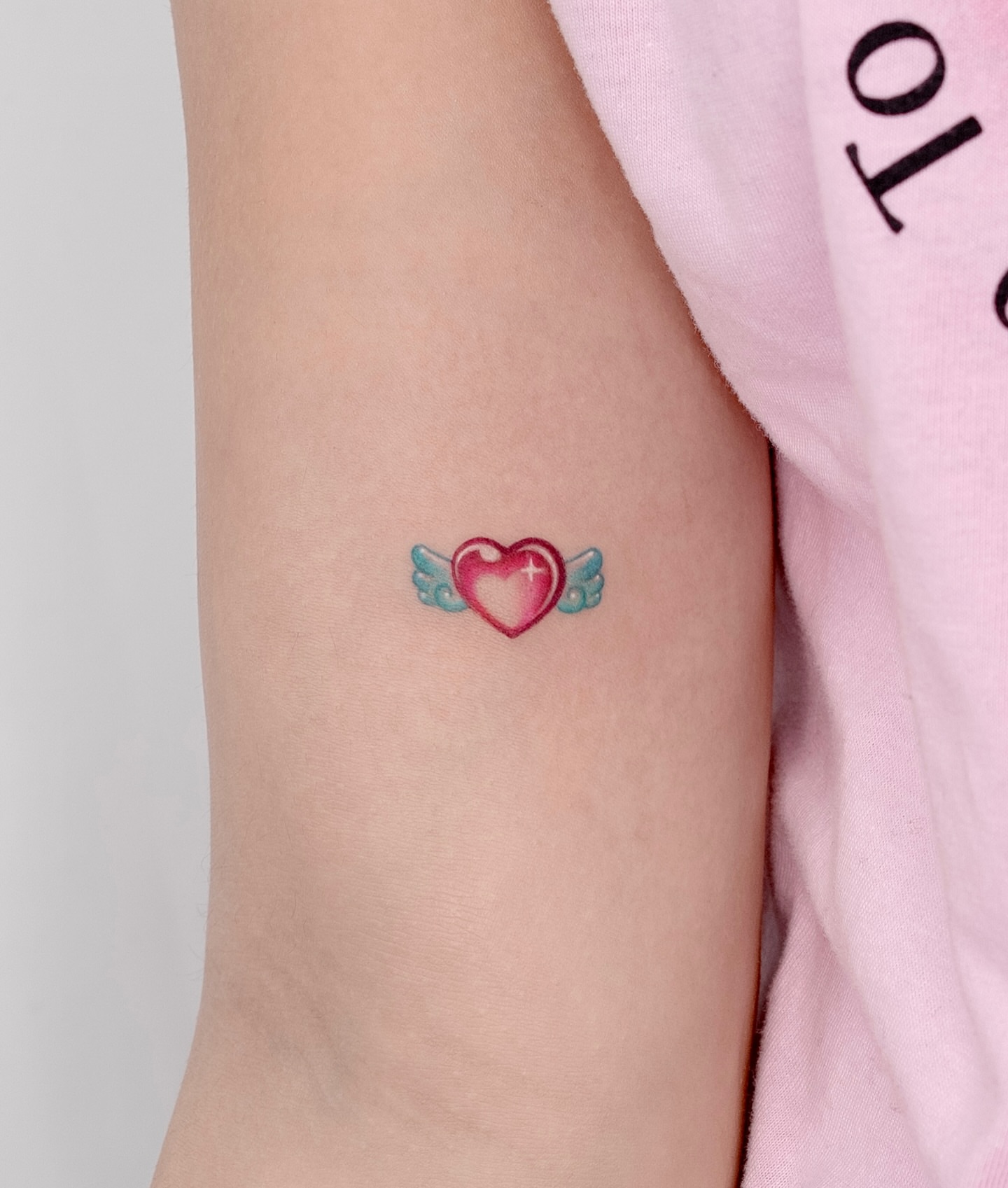 Heart with wings watercolor tattoo on the forearm by 라이브 Live