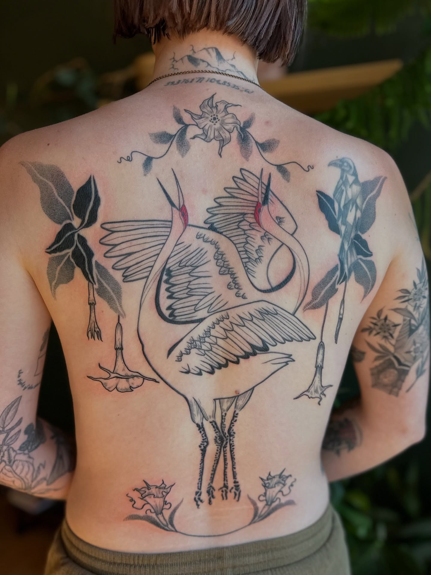 Flamingo and floral black and grey tattoo on the back by Alexandra Gray