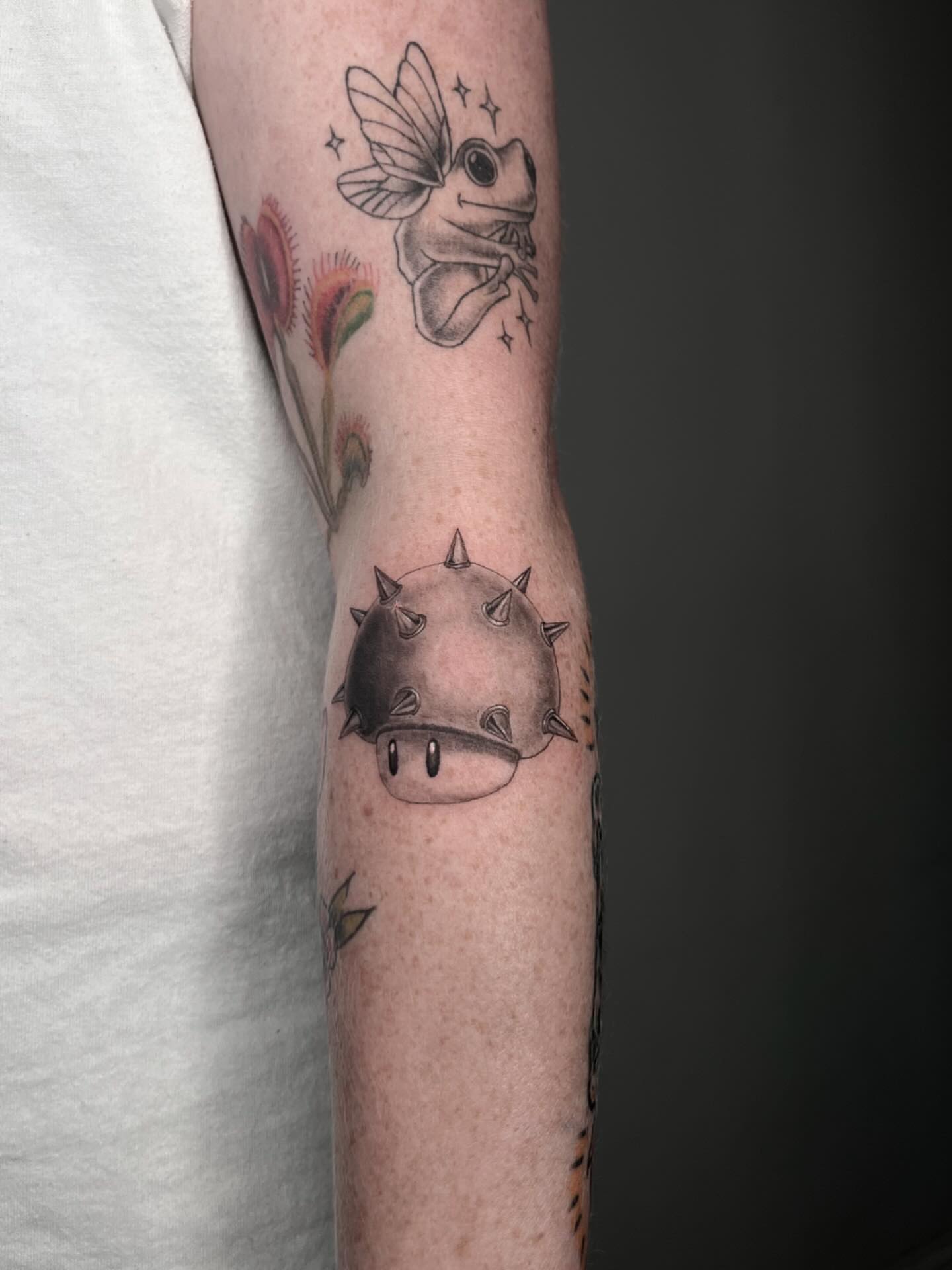 Frog with butterfly wings black and grey tattoo on the forearm by Anthony “Jiinky” Quintanilla 🧸☁️