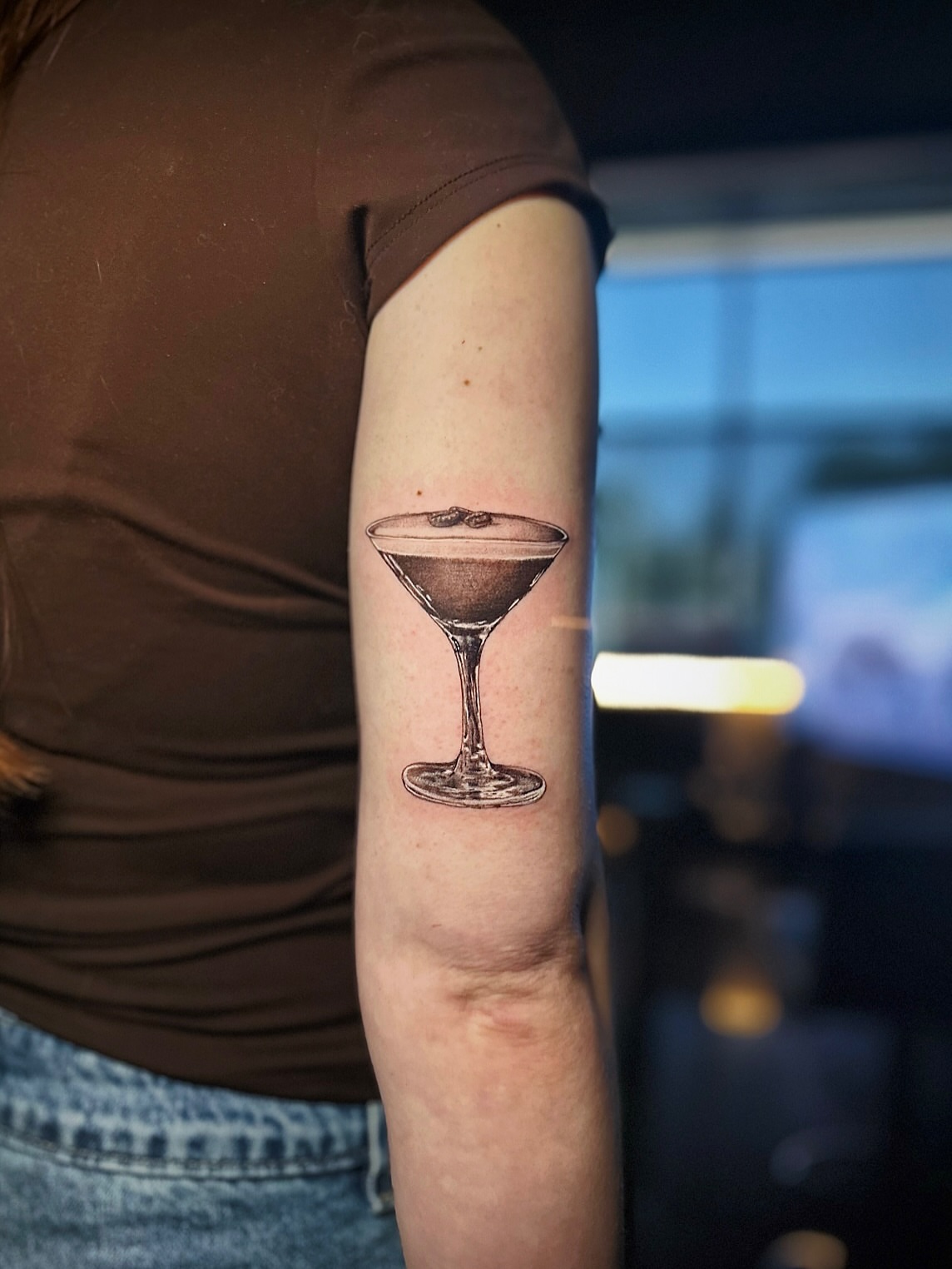 Martini glass realism tattoo on the forearm by Kelsey Zussman