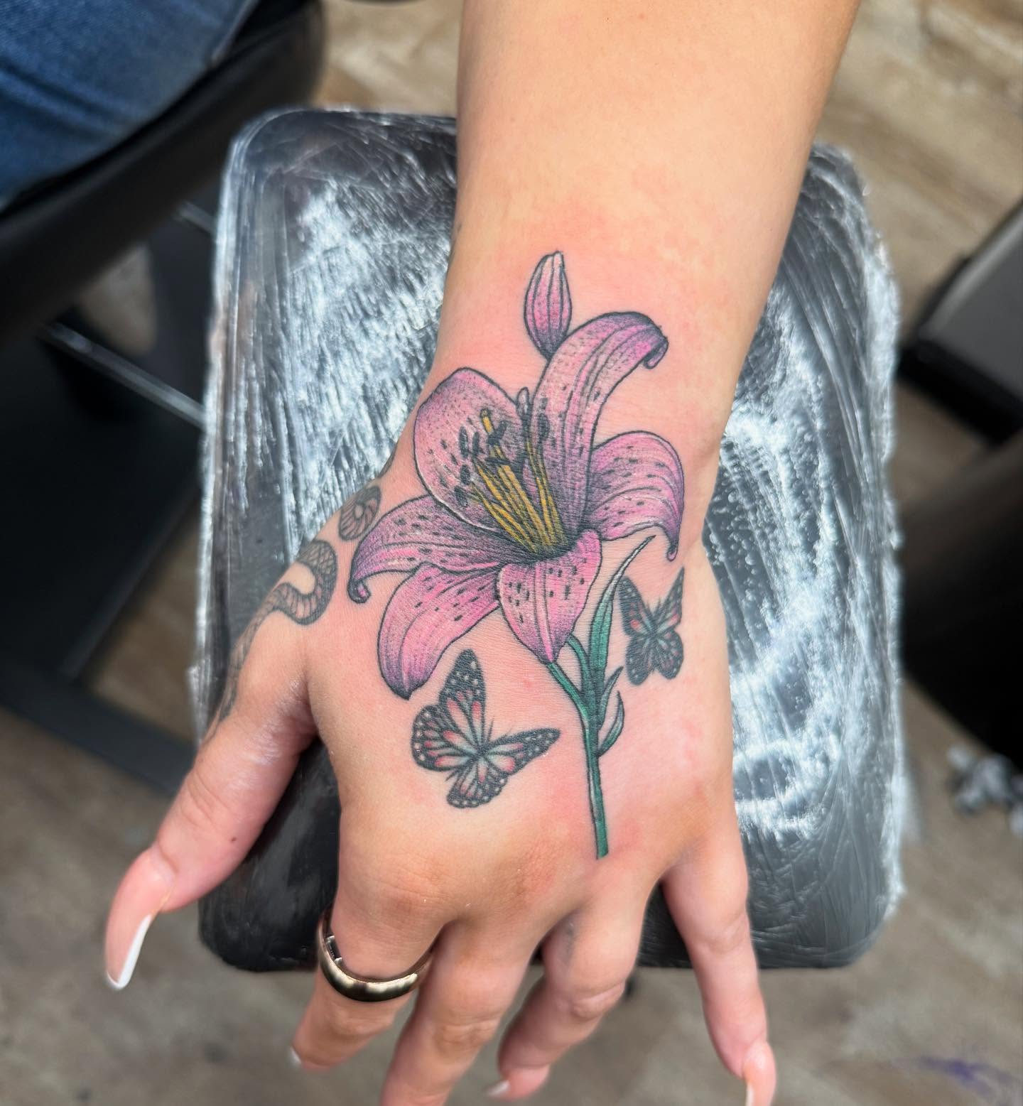 Lily and butterflies realism tattoo on the hand by Alejandro Juarez