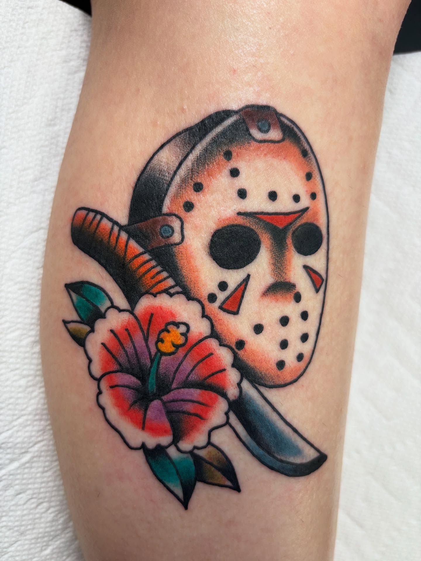 Jason mask and flower American traditional tattoo on the forearm by Ben Whyte