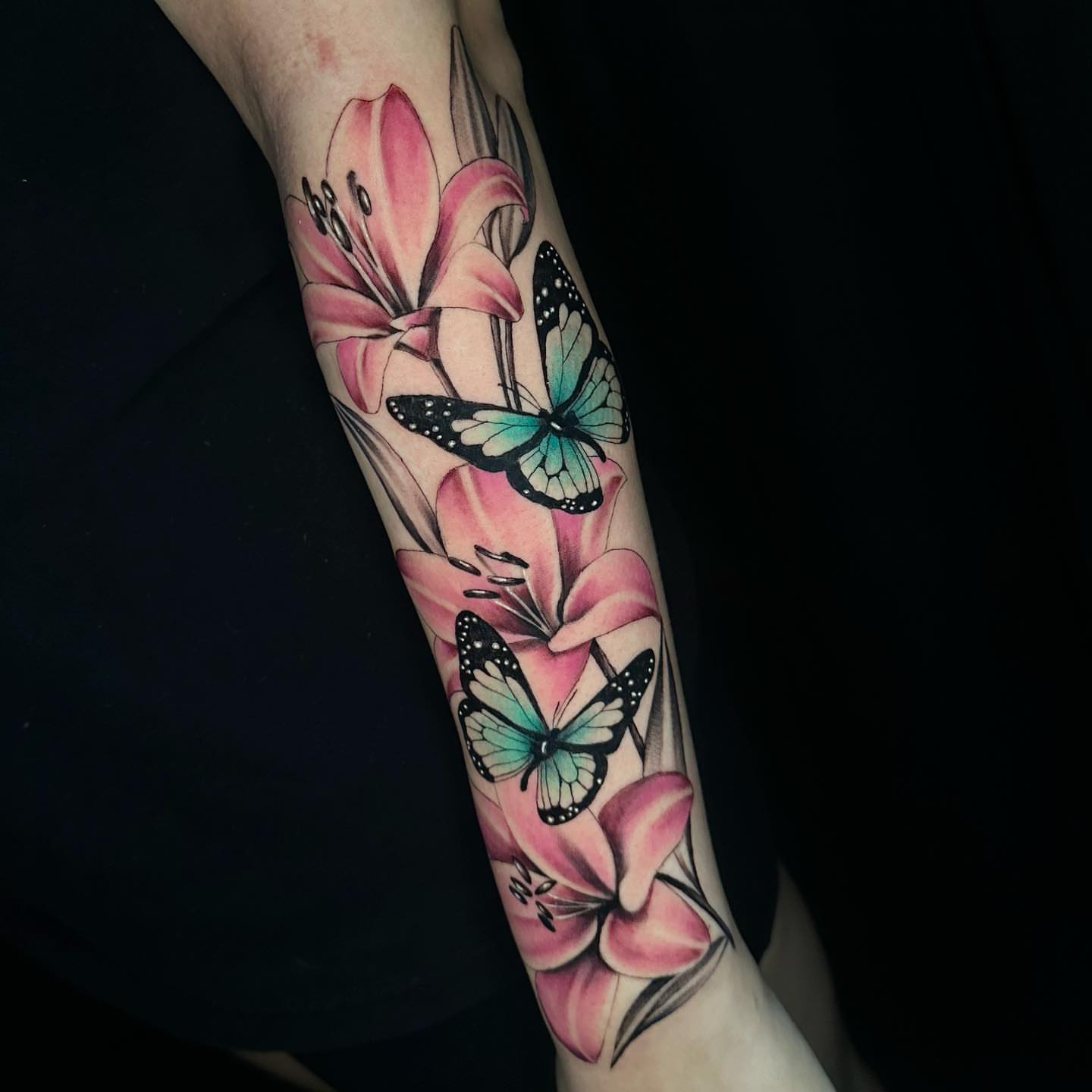 Lilies and butterflies realism tattoo on the forearm by Angela Azure