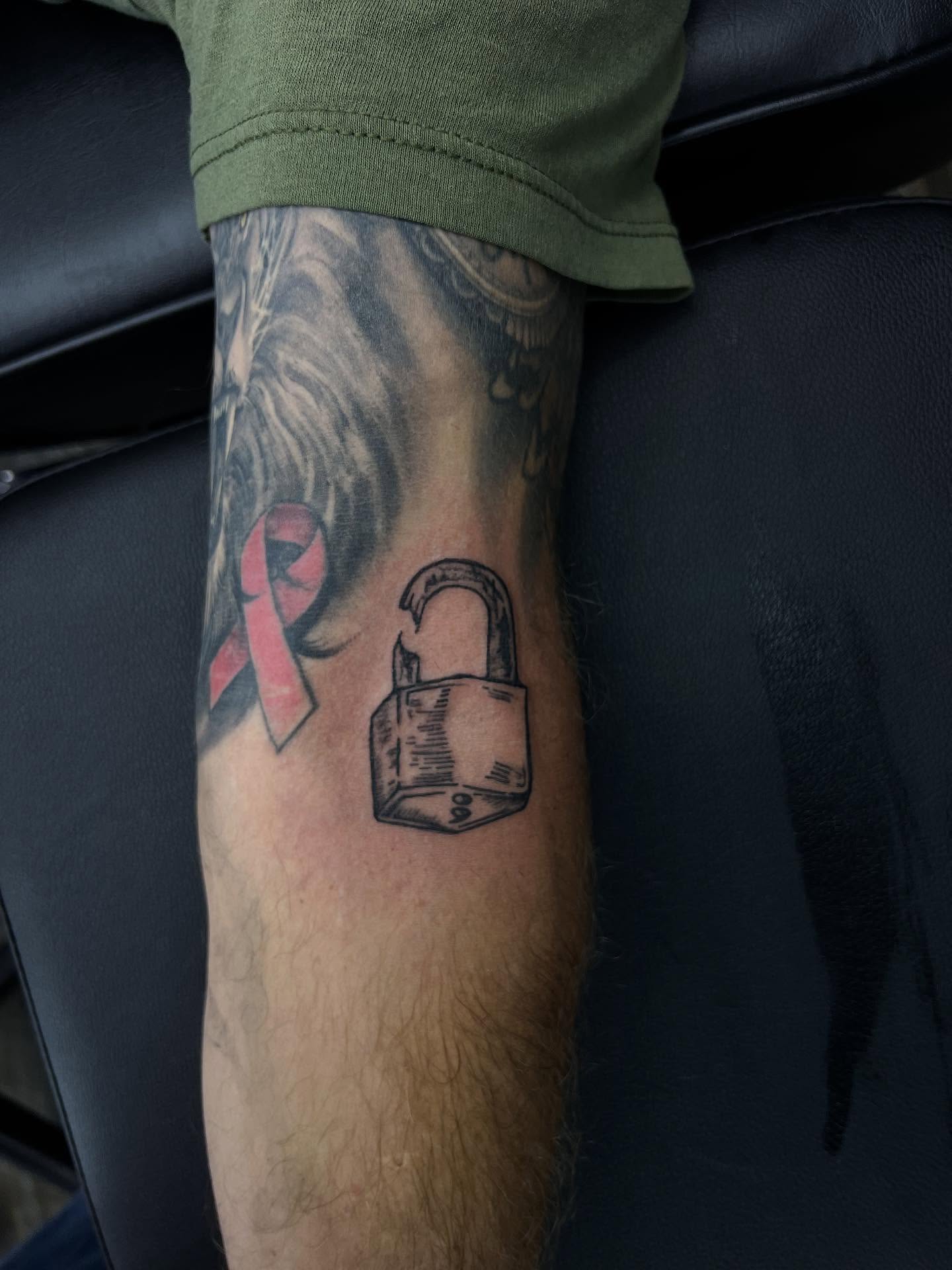 Red ribbon and padlock black and grey tattoo on the forearm by ★𝐑𝐮𝐞★