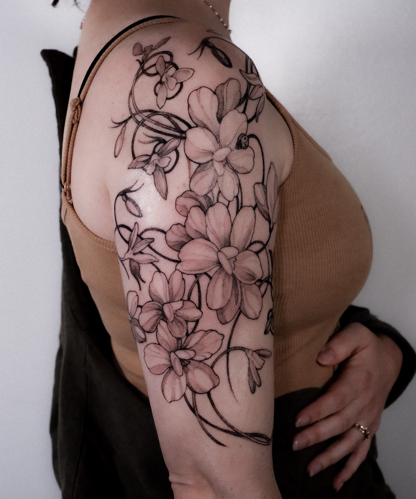 Flowers black and grey tattoo on the upper arm by Alena Zozulenko
