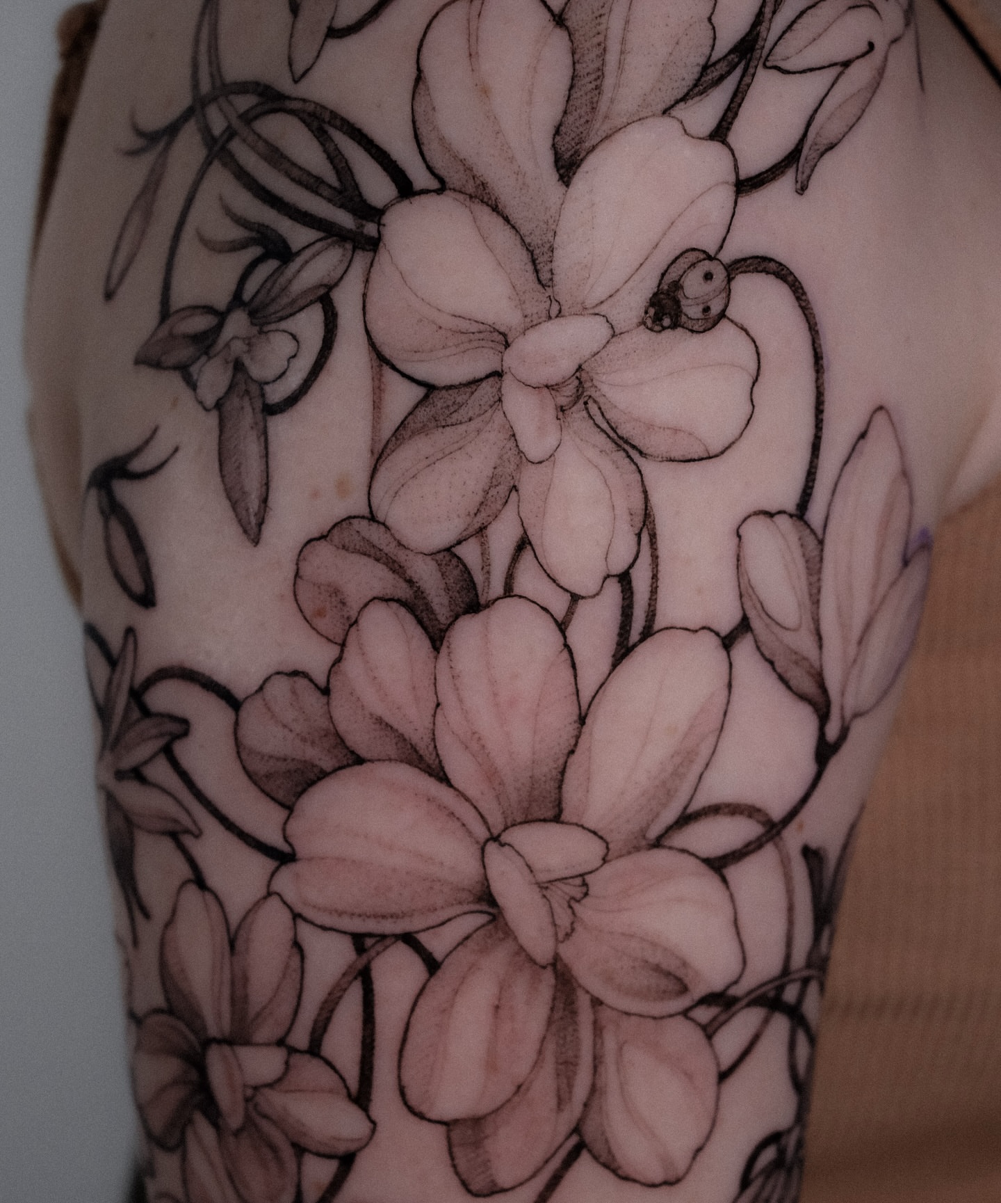 Flowers black and grey tattoo on the upper arm by Alena Zozulenko