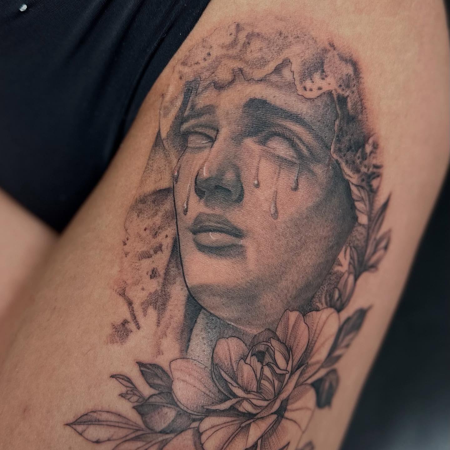 Weeping face with flowers realism tattoo on the thigh by Antonio