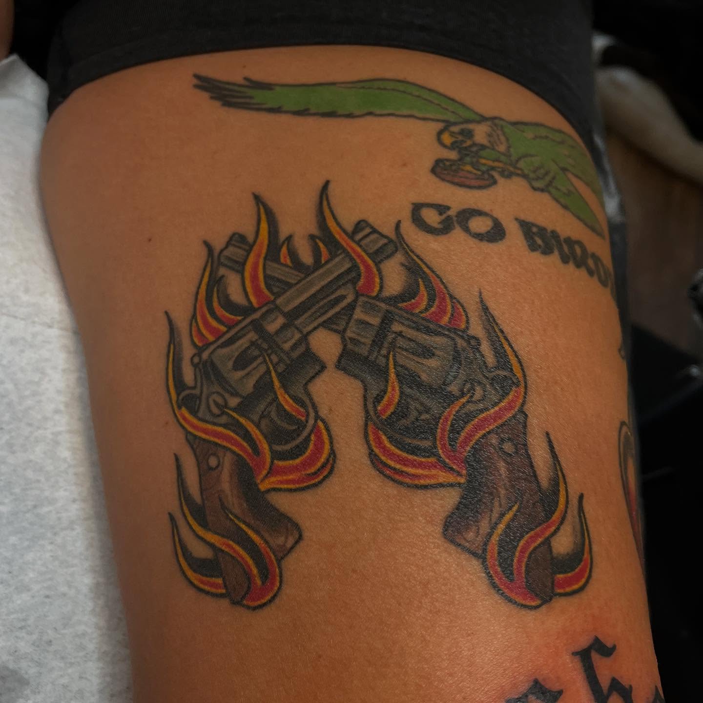 Guns and flames American traditional tattoo on the thigh by Adam Habecker