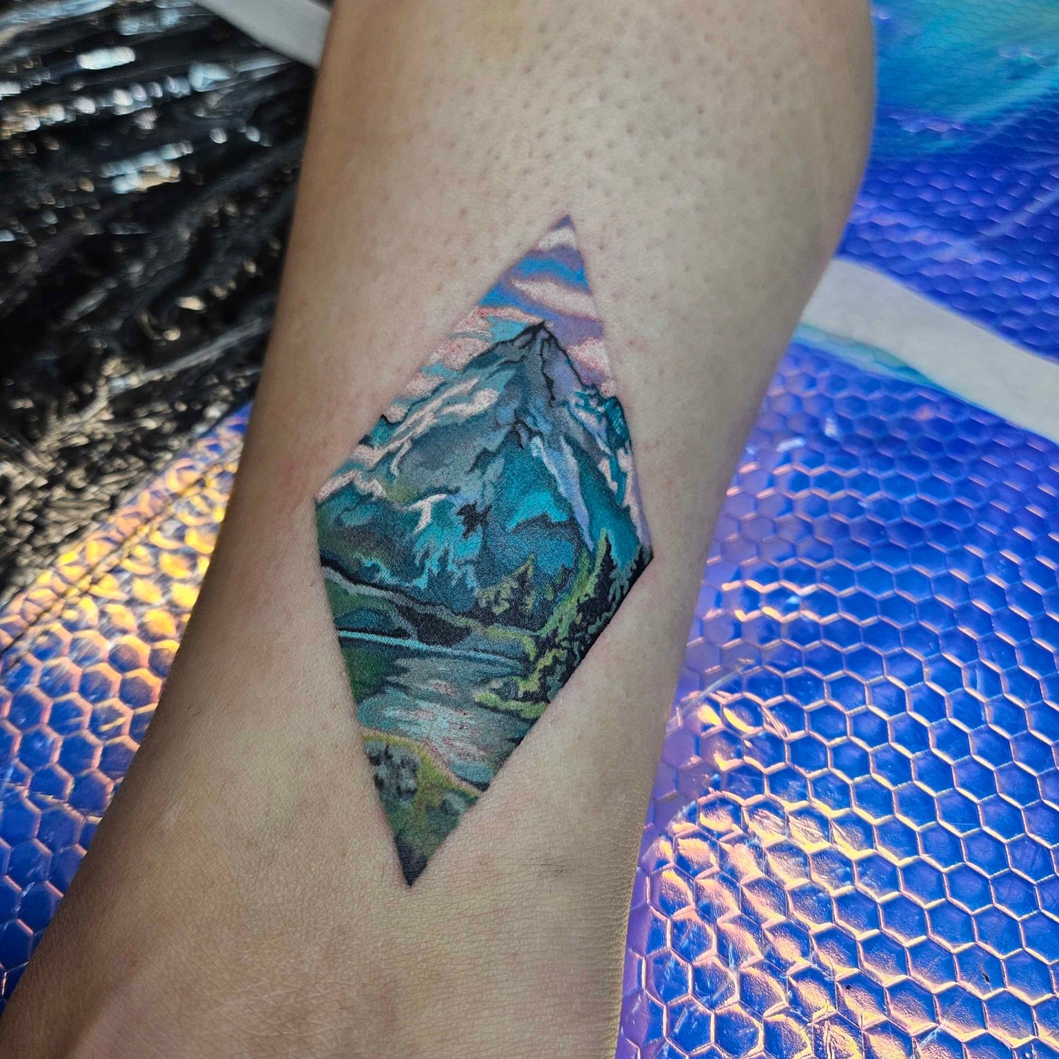 Mountain landscape watercolor tattoo on the forearm by Iram Withencroft