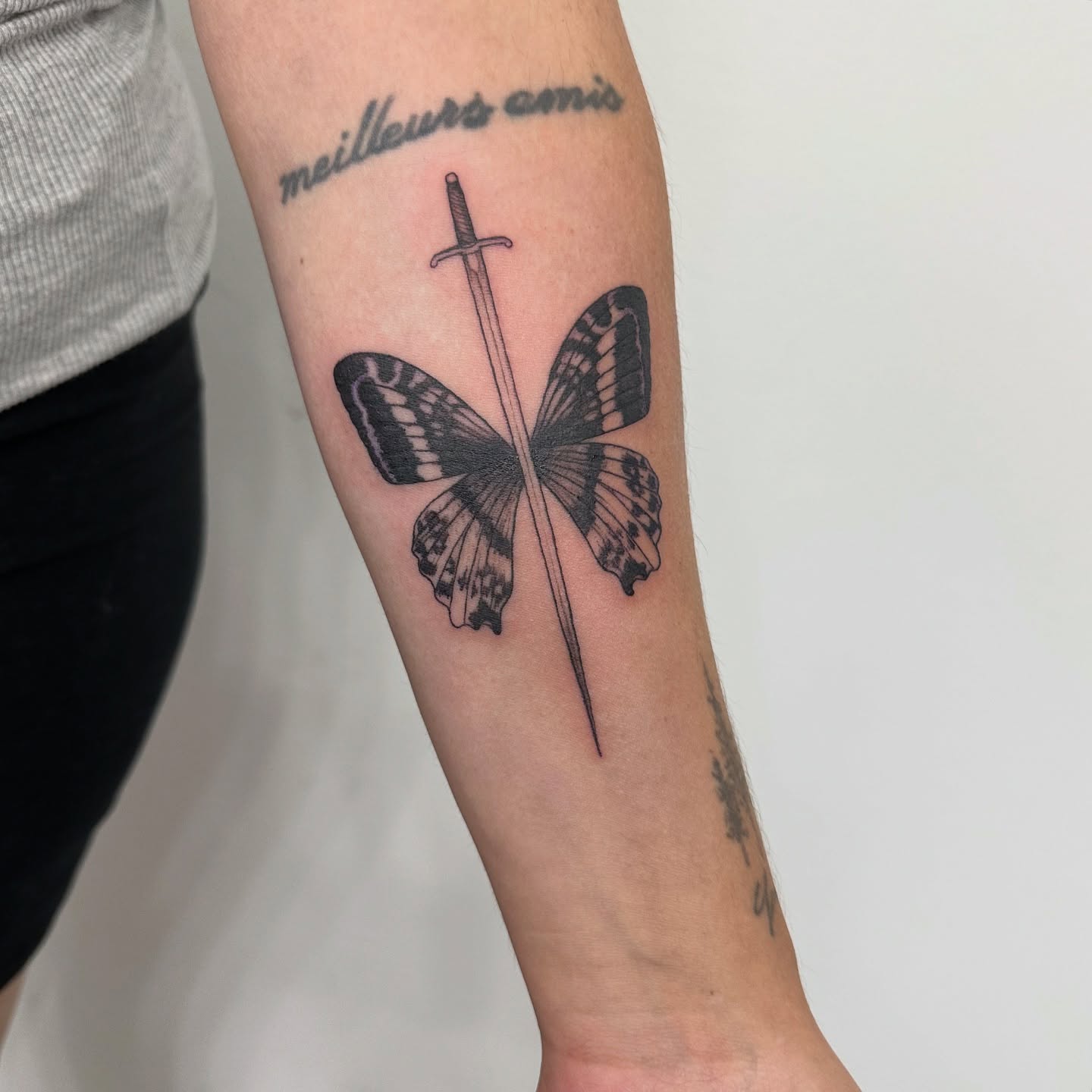 Butterfly and sword black and grey tattoo on the forearm by ๐ฌ๐๐๐ฏ๐ ๐ฆ ๐๐ฉ๐ฆ๐ท๐๐๐ข๐ฑ๐ฅ ๐ซง๐ผ, Joplin, Missouri