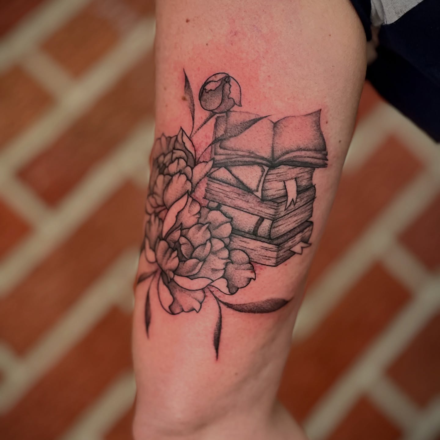 Book and flowers black and grey tattoo on the forearm by Dani McBay