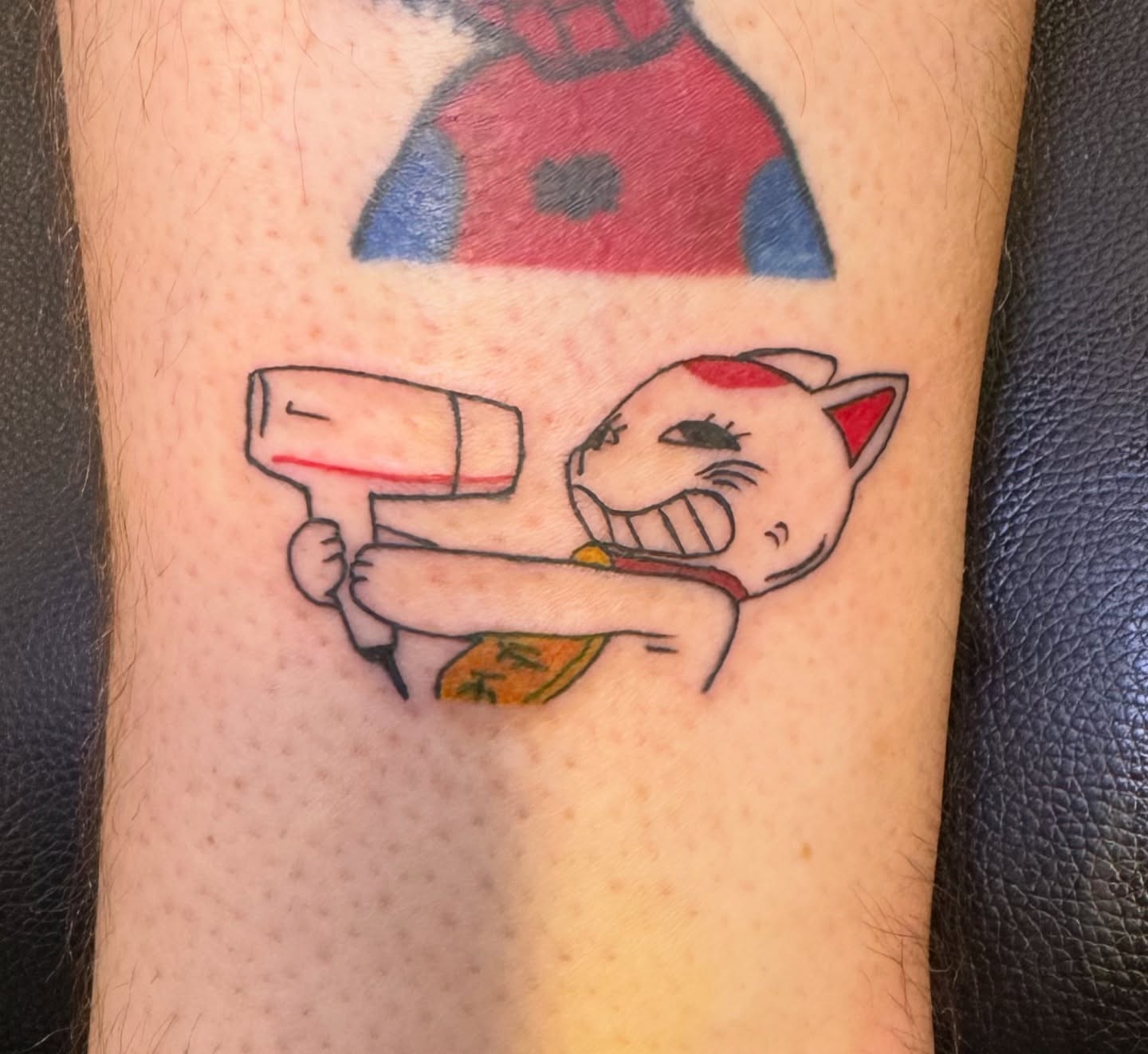 Cat with drill anime tattoo on the forearm by Minxxy Tattoos