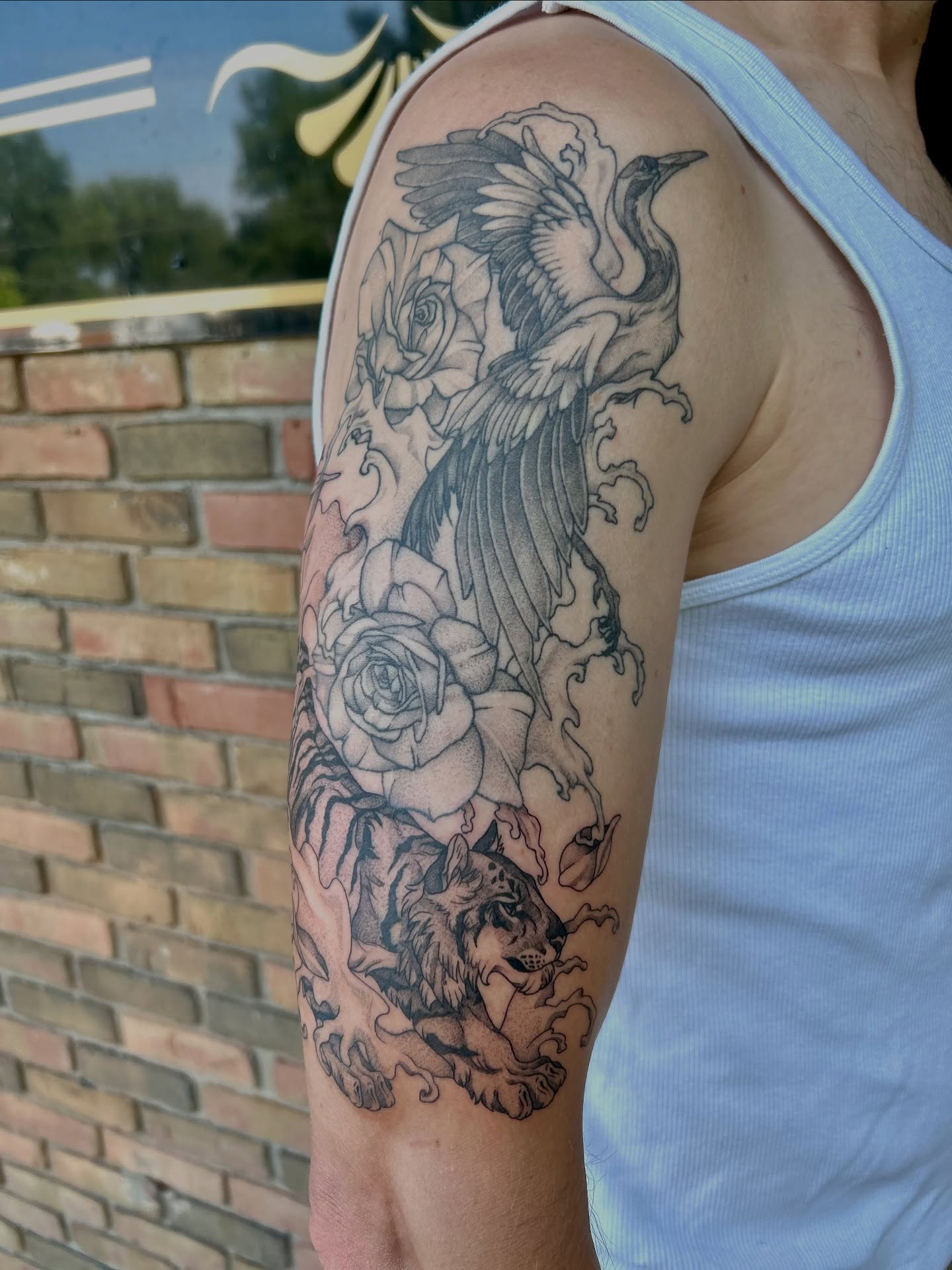 Bird and roses black and grey tattoo on the upper arm by Taylor Heidtbrink