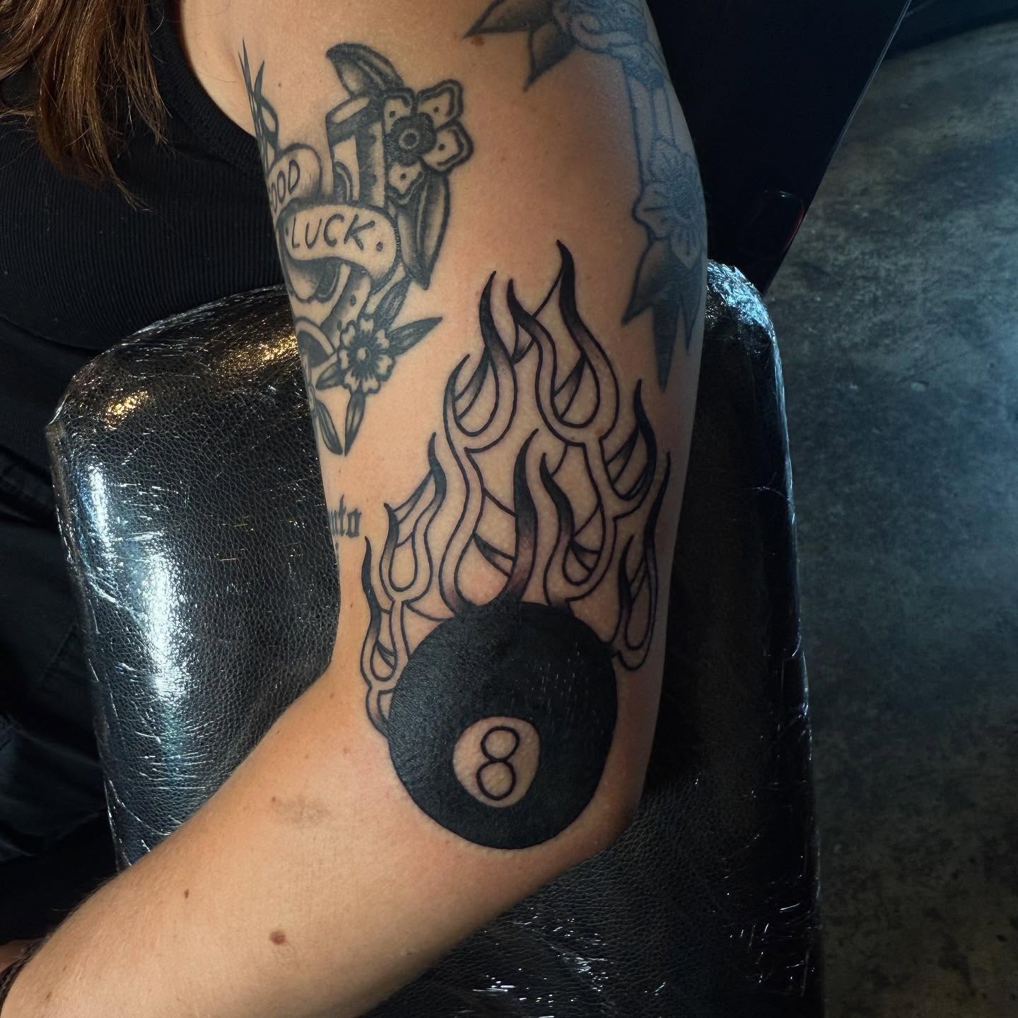 Flaming eight ball black and grey tattoo on the forearm by frankie quadrini