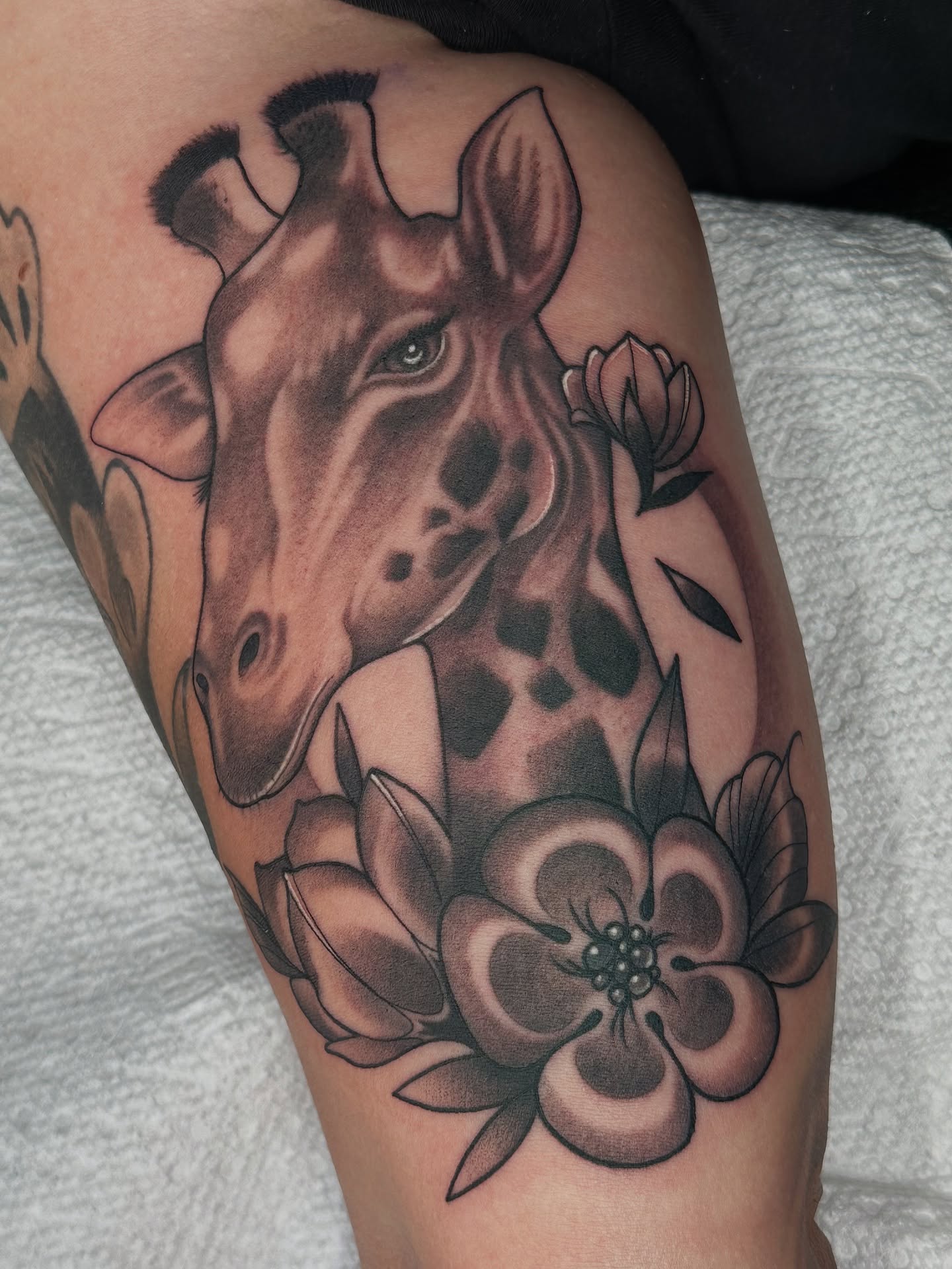 Giraffe and flowers realism tattoo on the thigh by B.G. Germershausen