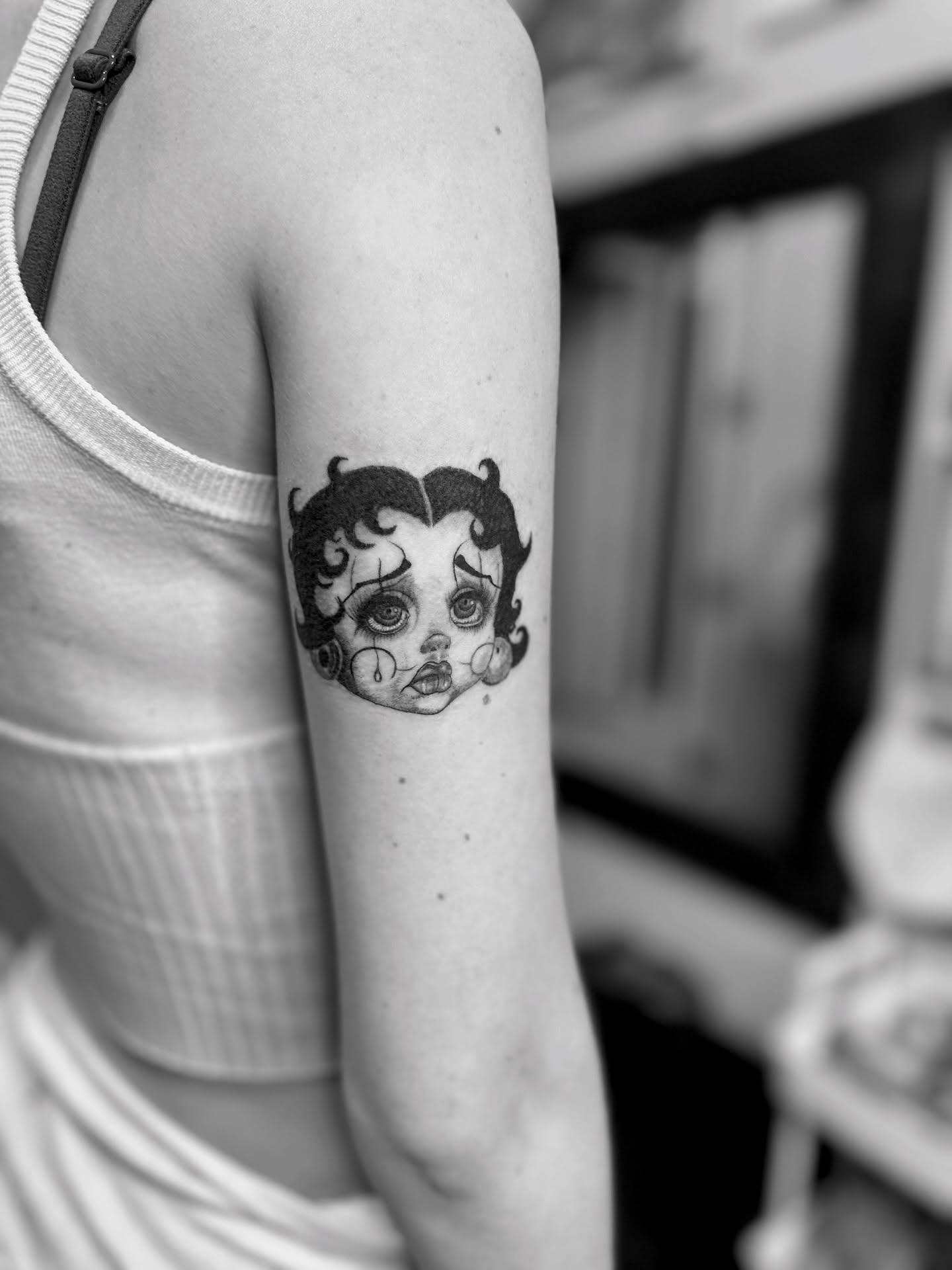 Doll head black and grey tattoo on the forearm by Roxanne Ochoa
