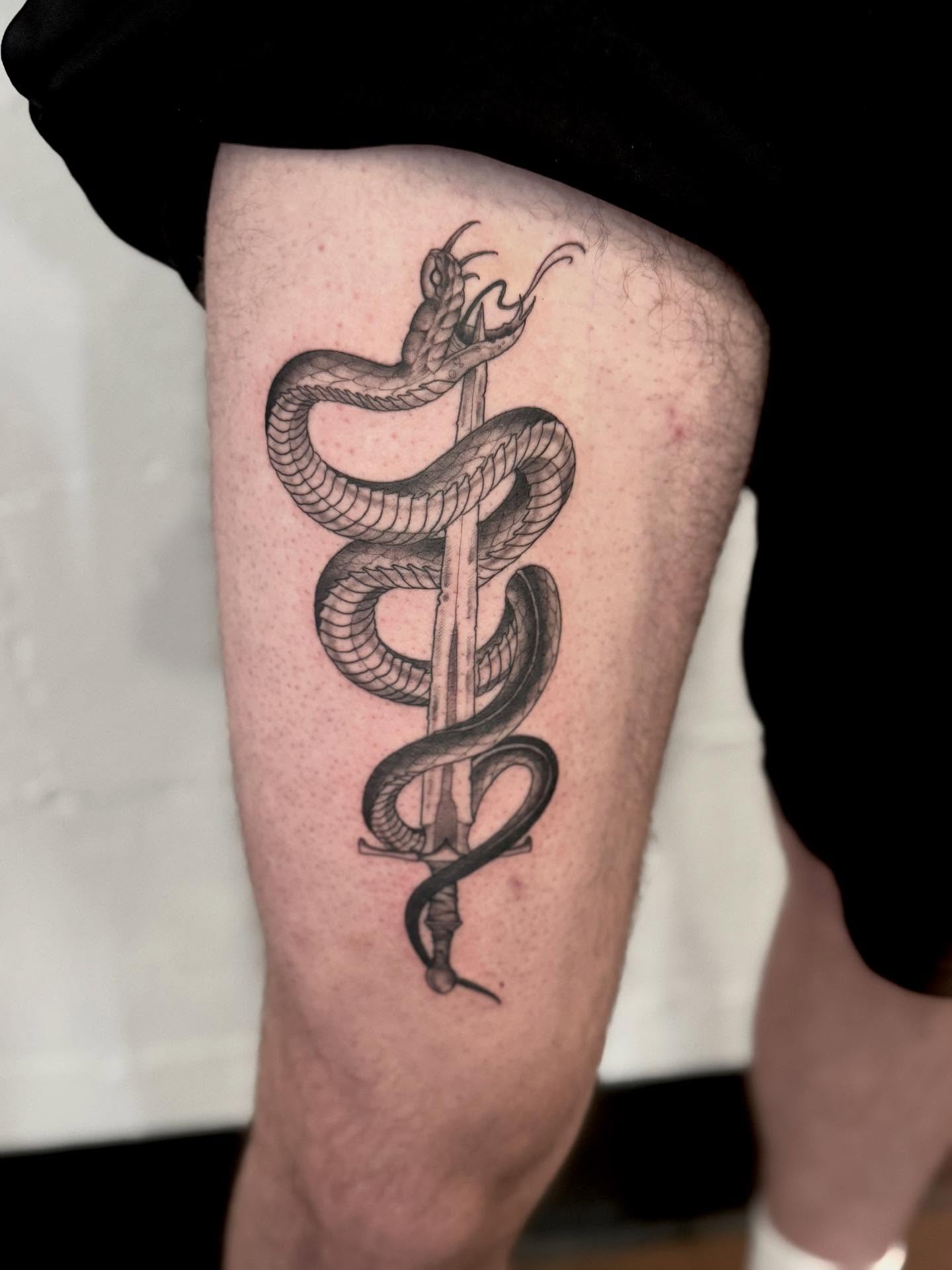 Snake and sword black and grey tattoo on the thigh by Drew Foster, Toledo, Ohio