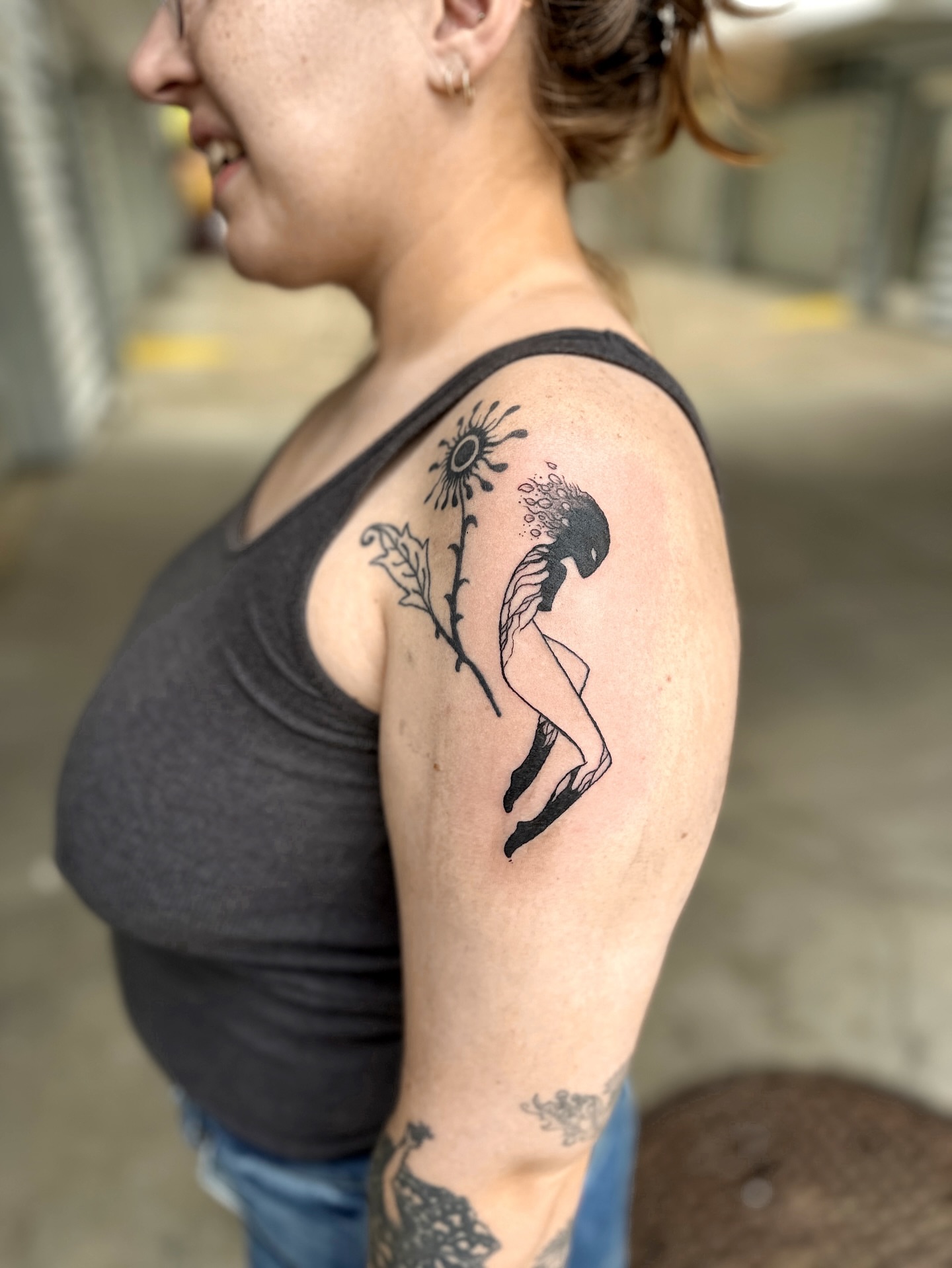 Sunflower and woman black and grey tattoo on the shoulder by Emma Berger
