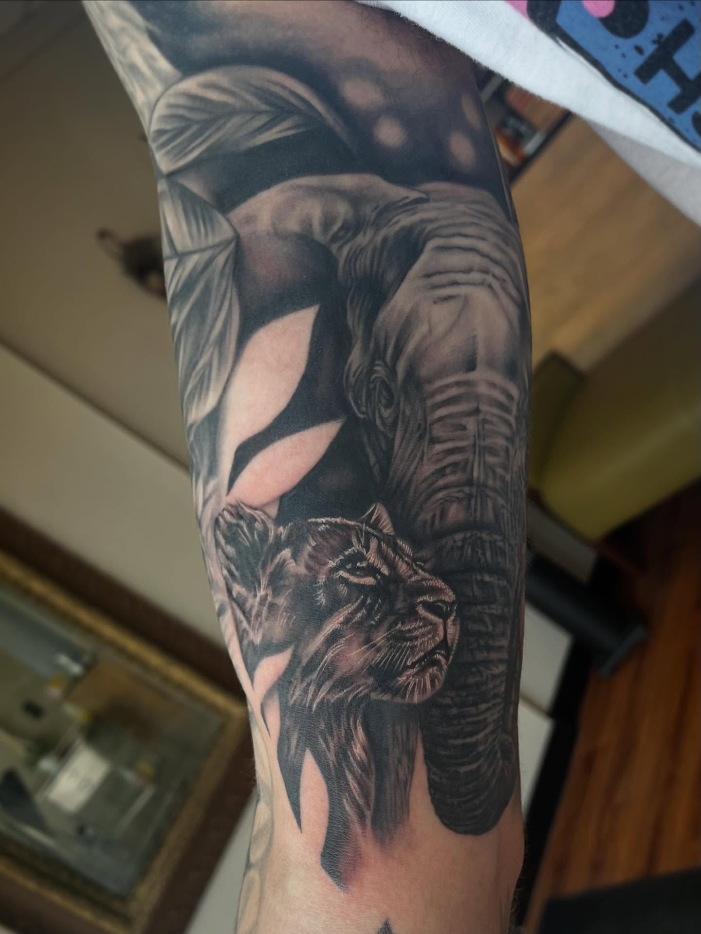 Elephant and lion realism tattoo on the forearm by Taylor Santavicca