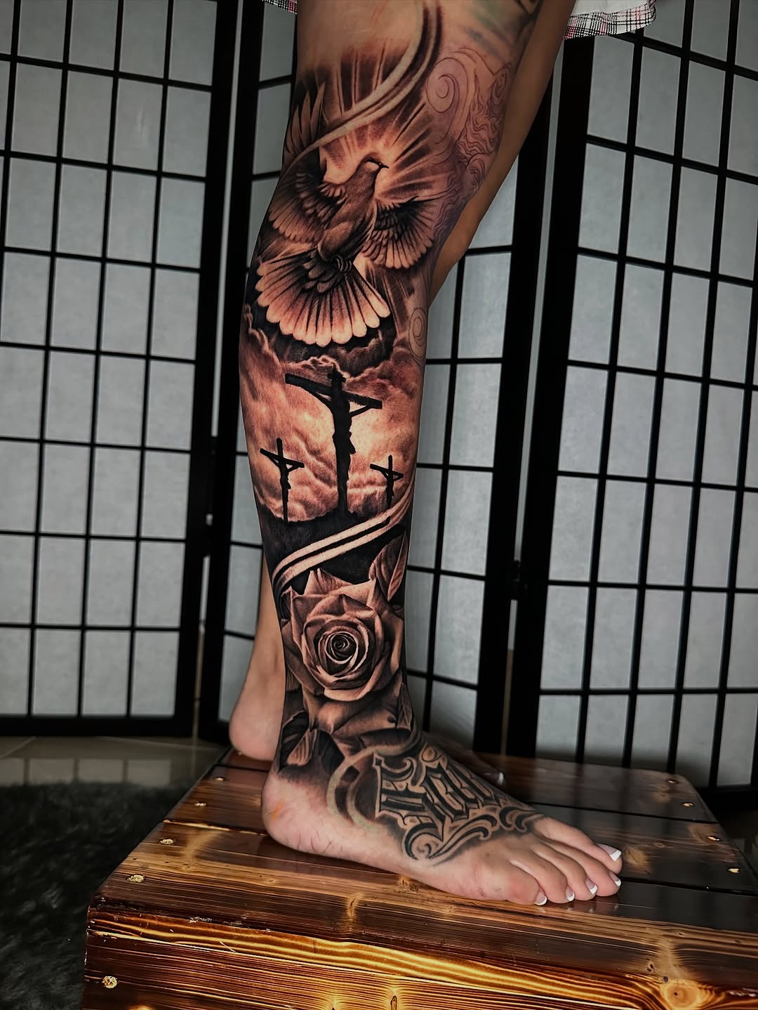 Dove, crucifixion, rose, lettering surrealism tattoo on the calf by Anthony Ramirez