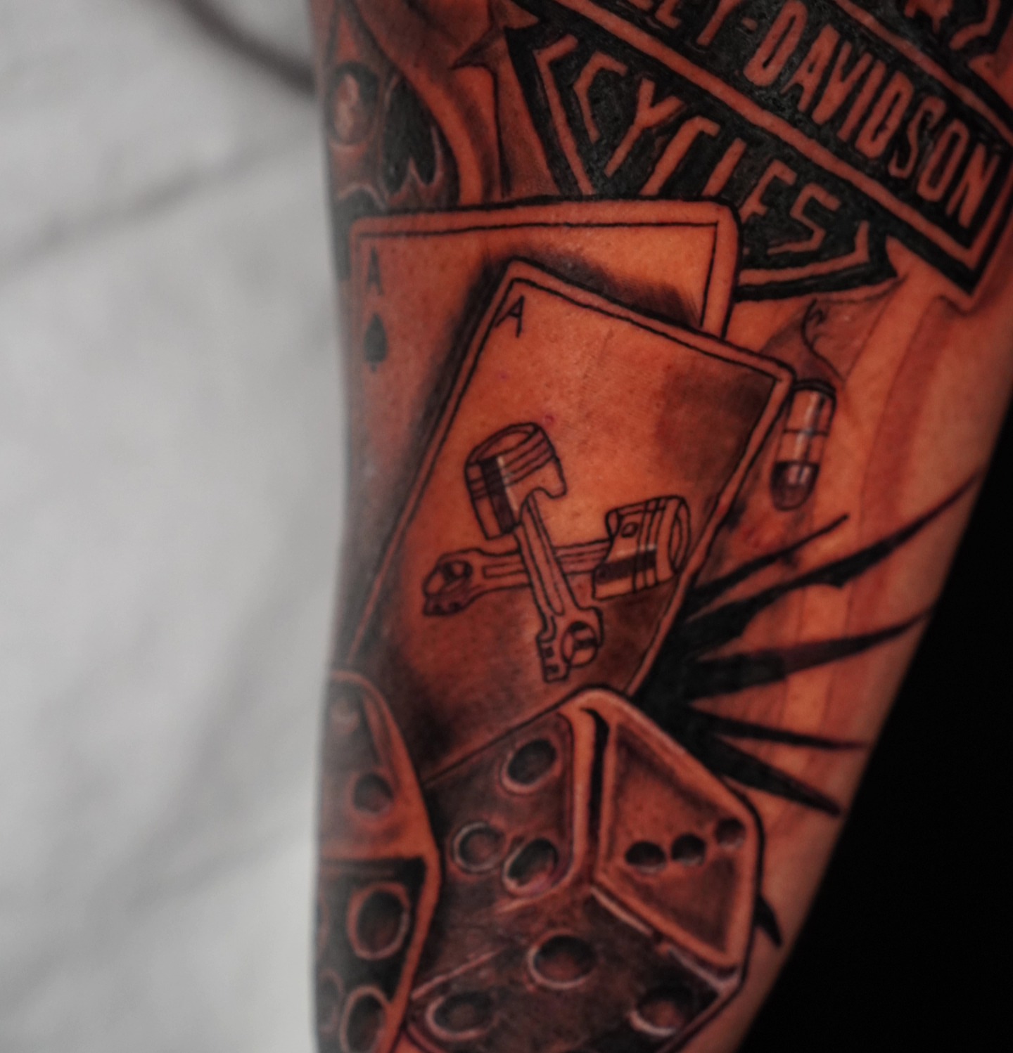 Playing cards and motorcycle parts realism tattoo on the forearm by @tattoobytats