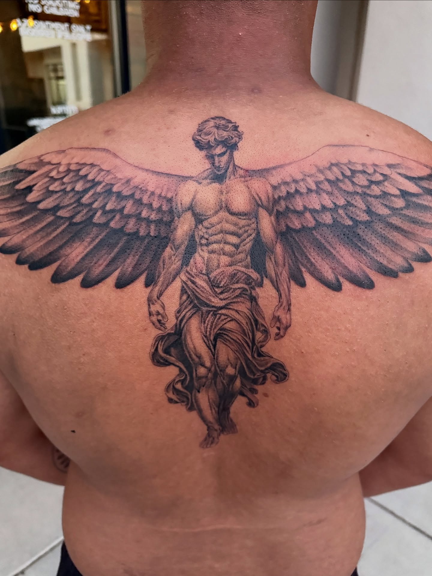 Statue of an angel realism tattoo on the back by Jevon Glasco Tattoos