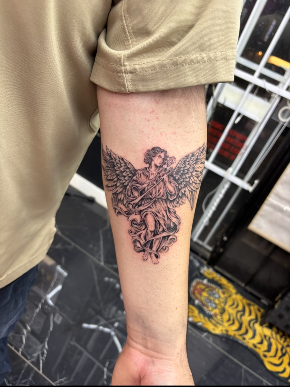 Angel with harp black and grey tattoo on the forearm by $weet little leslie 🩶🧚🏻‍♀️