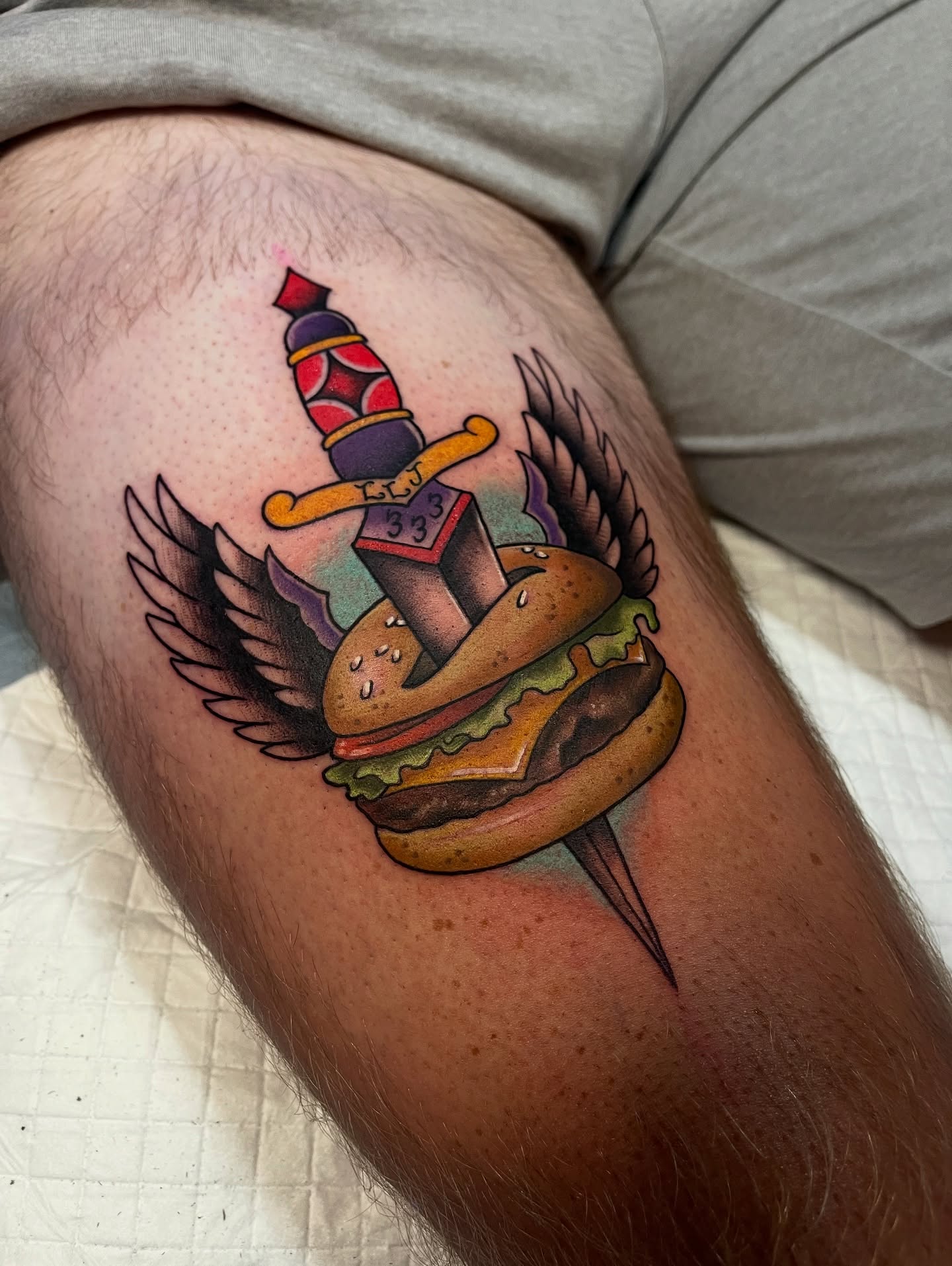 Burger and knife American traditional tattoo on the thigh by Brittany Welsh, Marlton, New Jersey