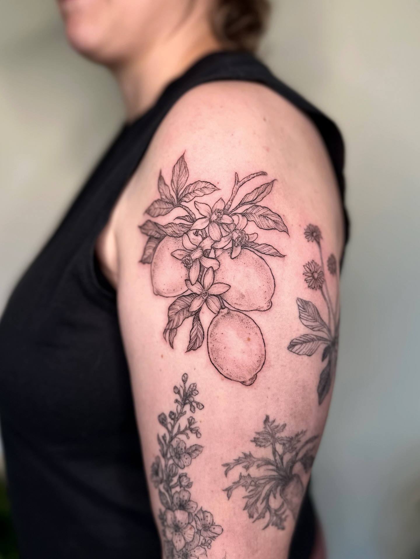 Lemons and flowers black and grey tattoo on the shoulder by kenzie hunter