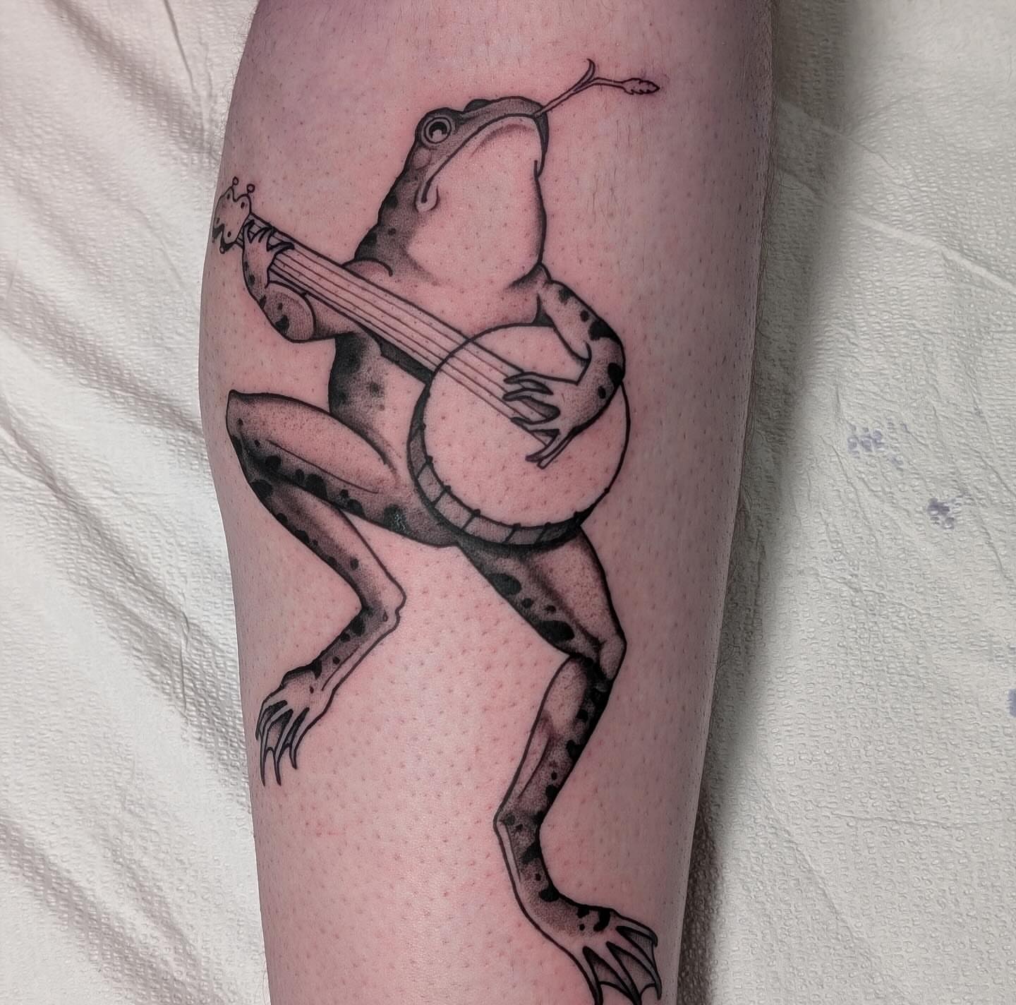 Frog playing banjo black and grey tattoo on the forearm by English Cousins, Nashville, Tennessee