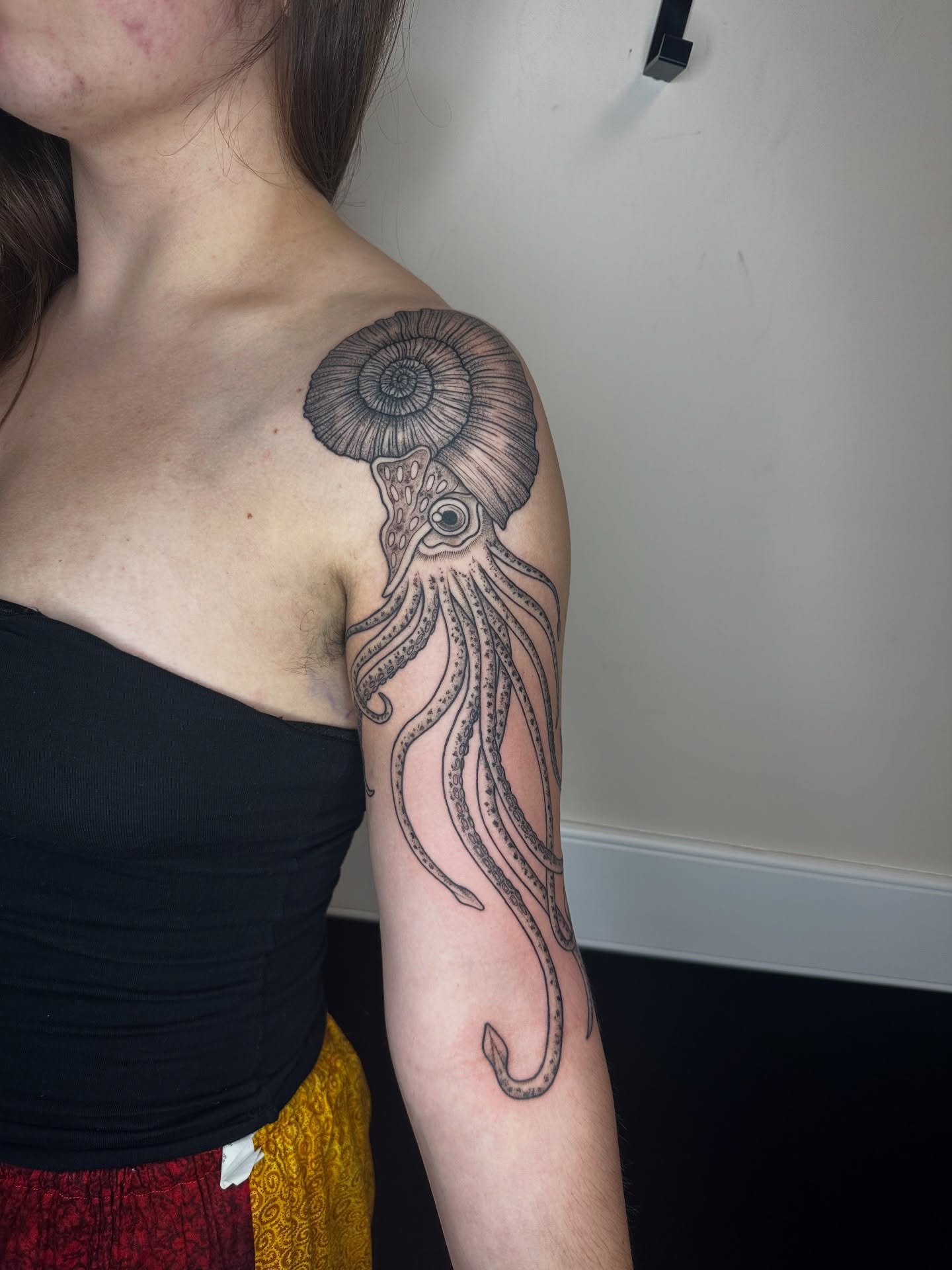 Squid with ammonite shell realism tattoo on the shoulder by sechi