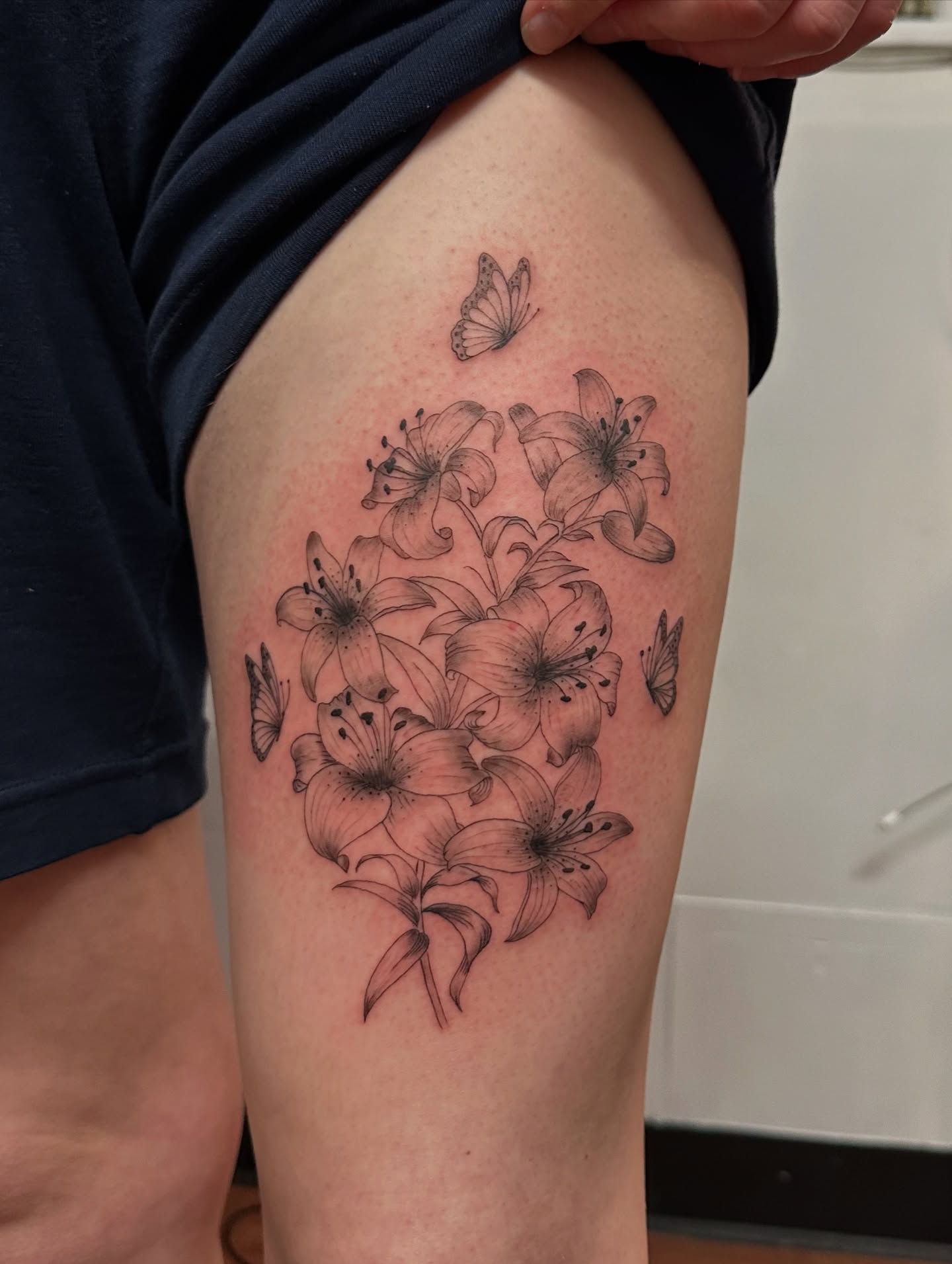 Lilies and butterflies black and grey tattoo on the thigh by Piccolino, Cambridge, Massachusetts