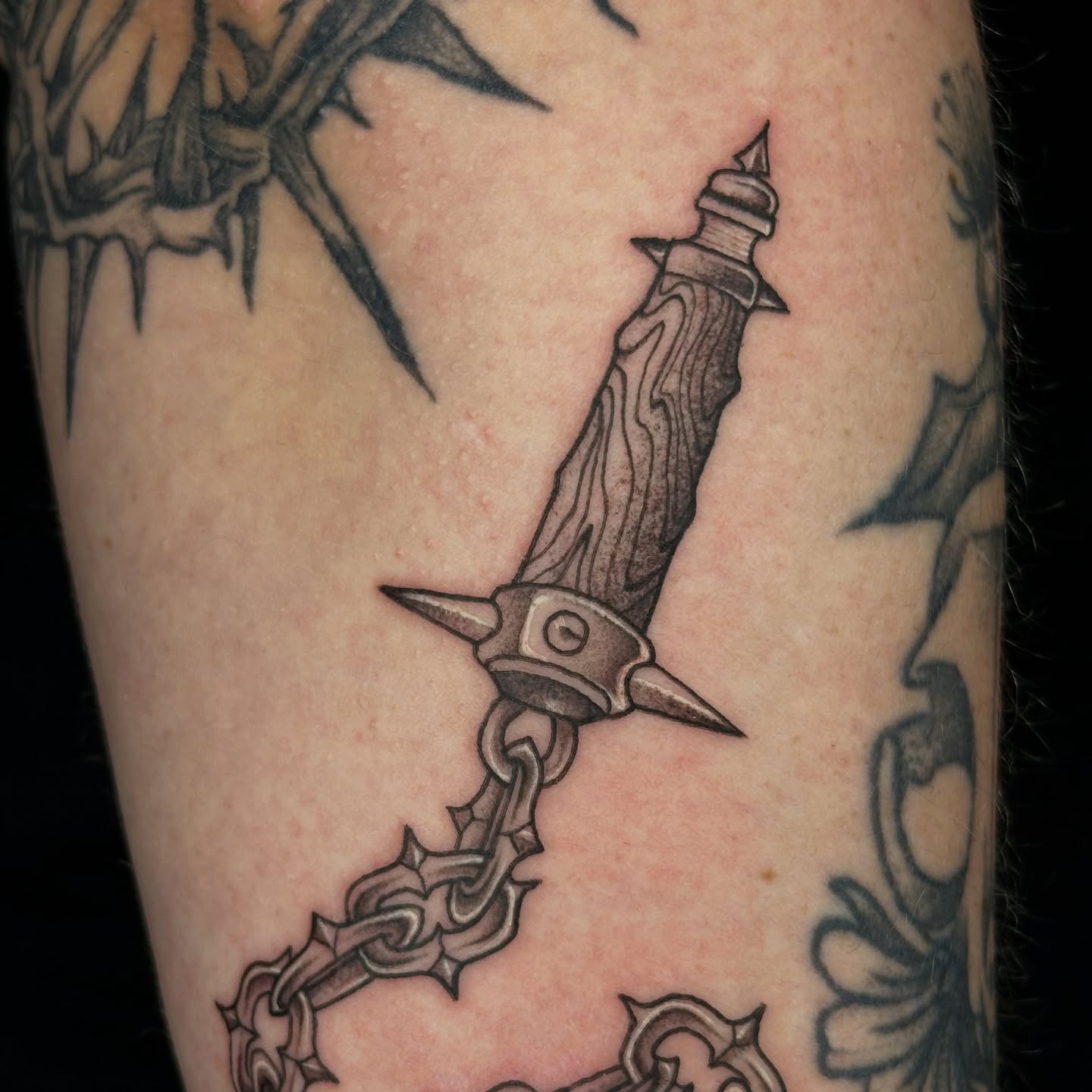 Knife and chain black and grey tattoo on the forearm by sechi